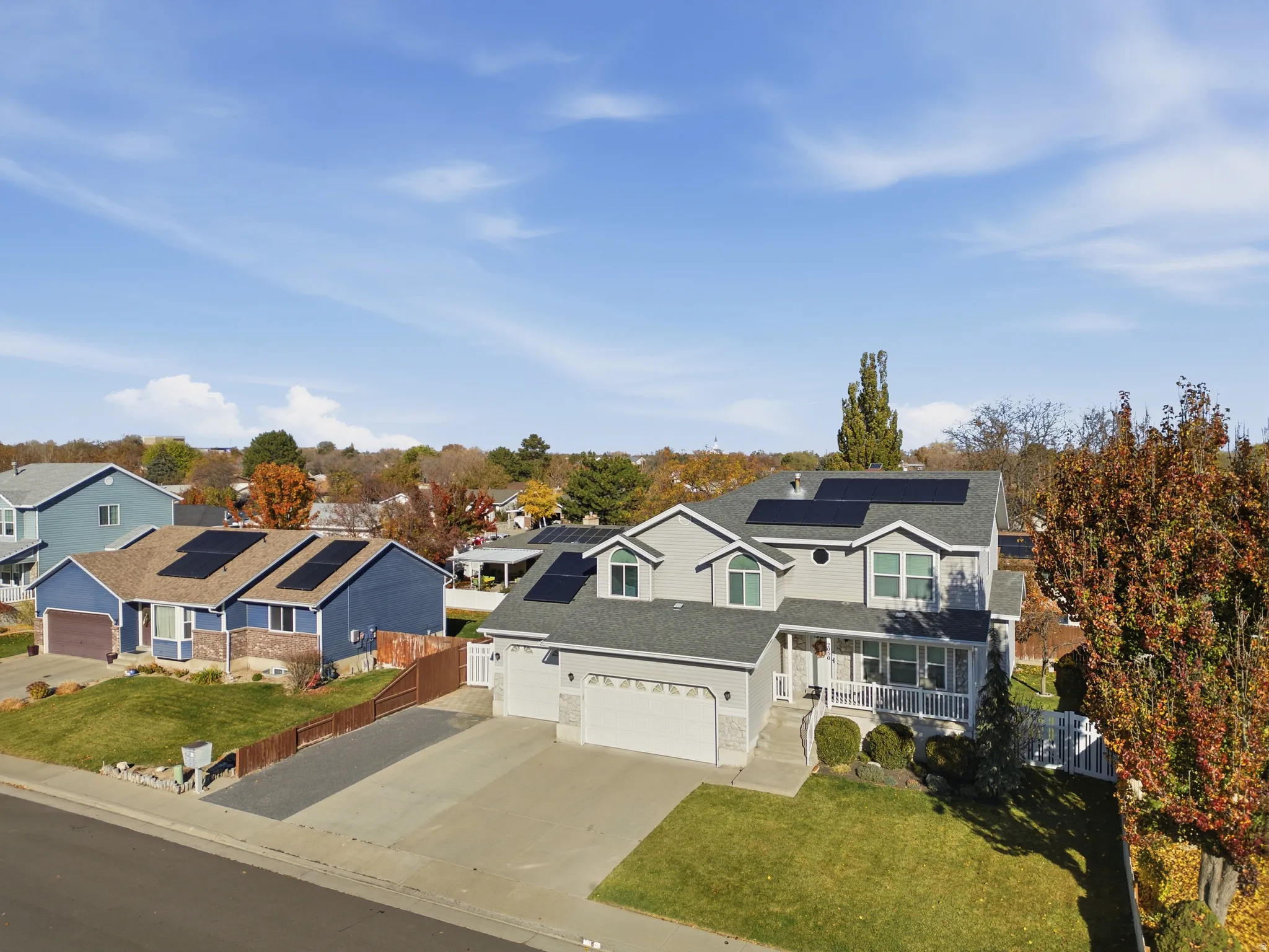Two-story gray exterior with solar panels, a covered front porch, and an attached two-car garage