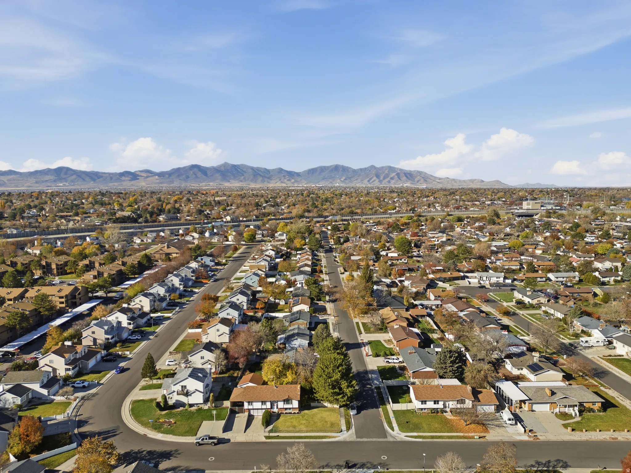 Expansive suburban neighborhood featuring a grid-pattern street layout, numerous single-family homes, and mature trees with autumn foliage