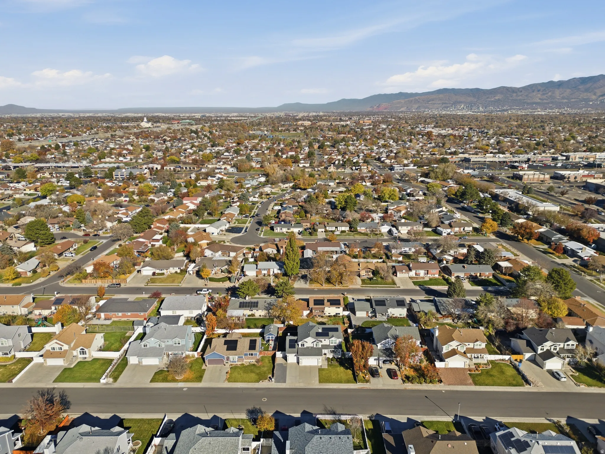 Expansive residential area featuring numerous single-family homes, mature trees with autumnal foliage, and paved streets