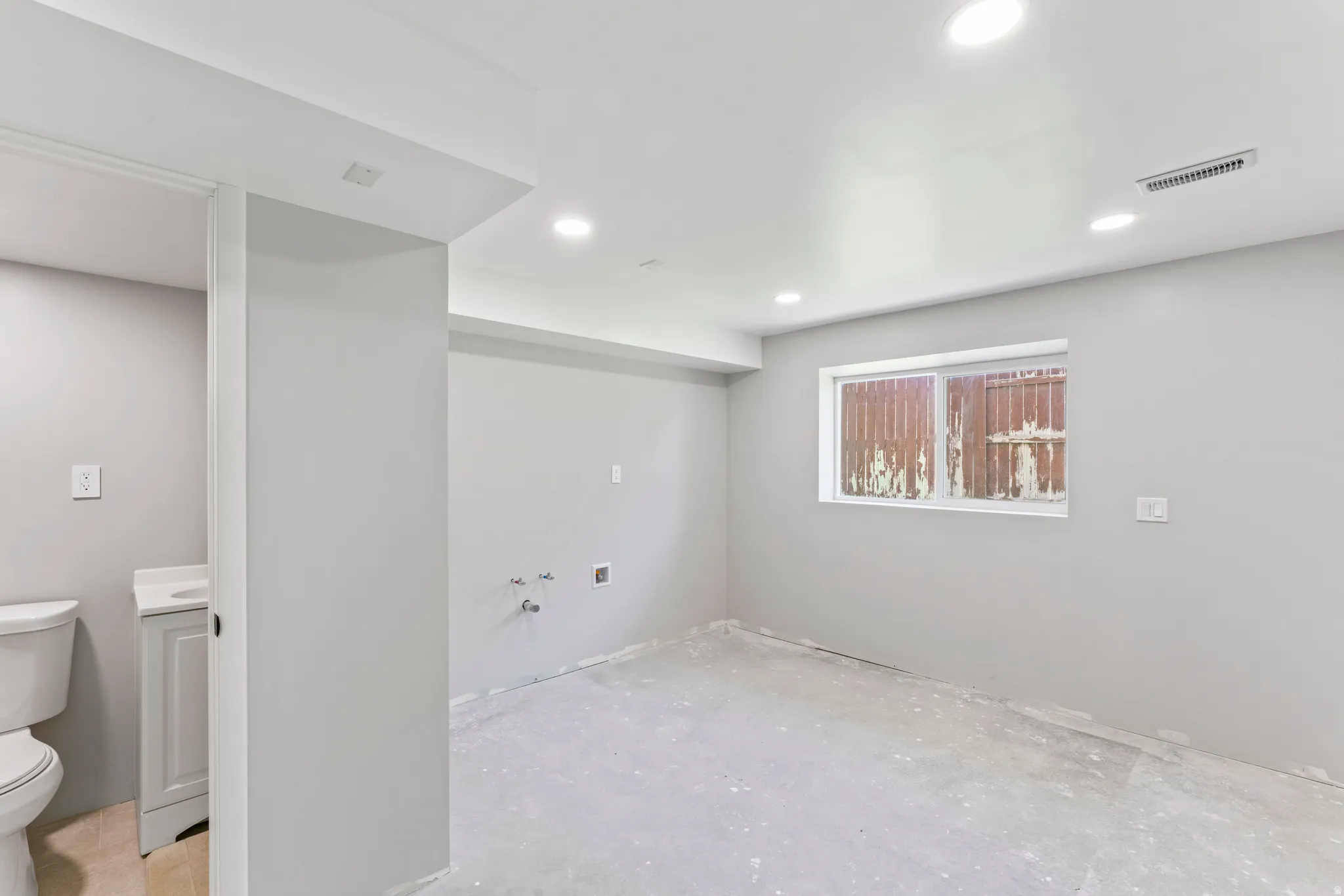 Open-concept space featuring a white window, recessed lighting, and light gray walls