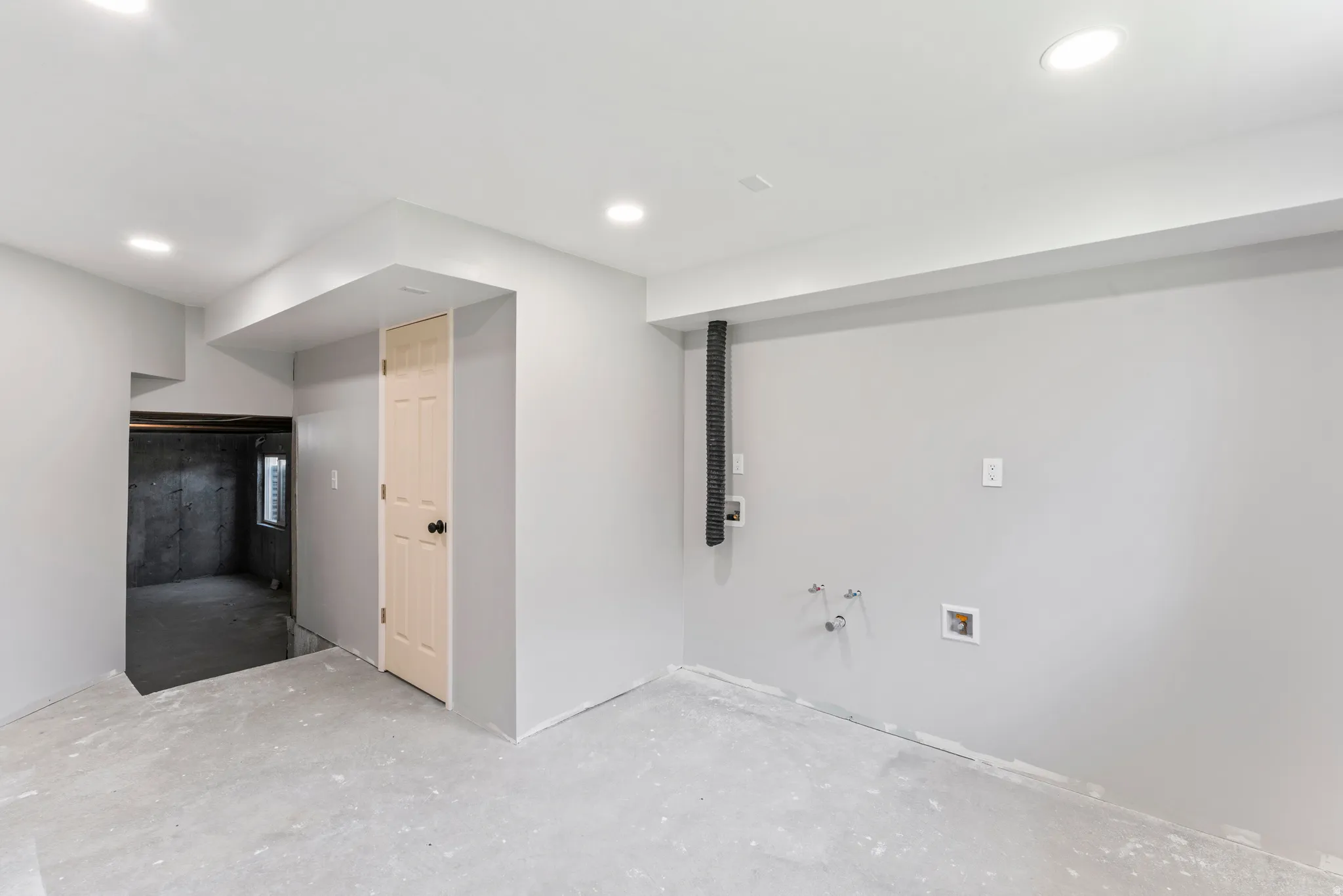 Spacious room featuring light gray walls, recessed lighting, concrete flooring, and a laundry hook-up area