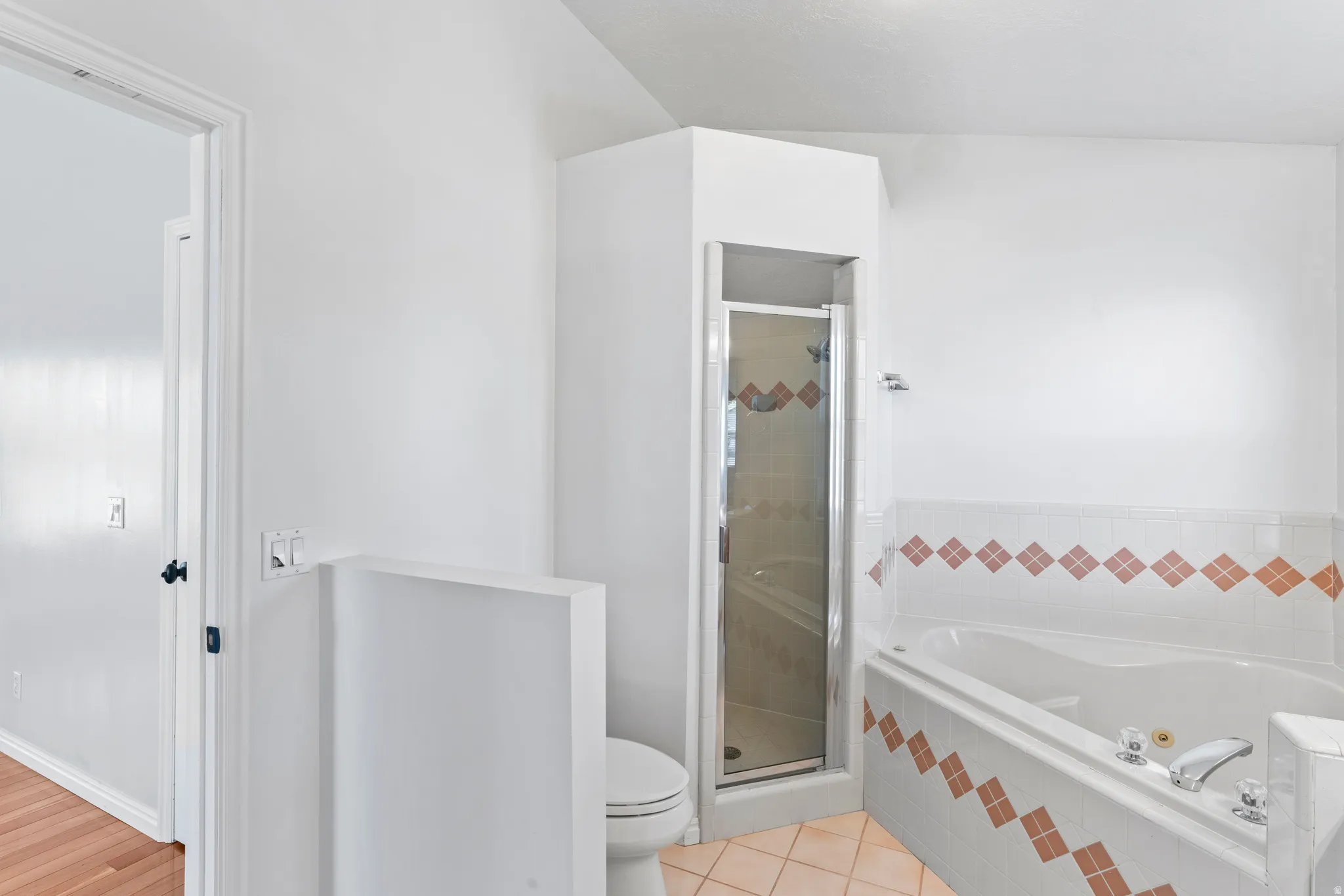 Bathroom featuring a corner glass-enclosed shower, a built-in jetted tub with tiled surround, and ceramic tile flooring