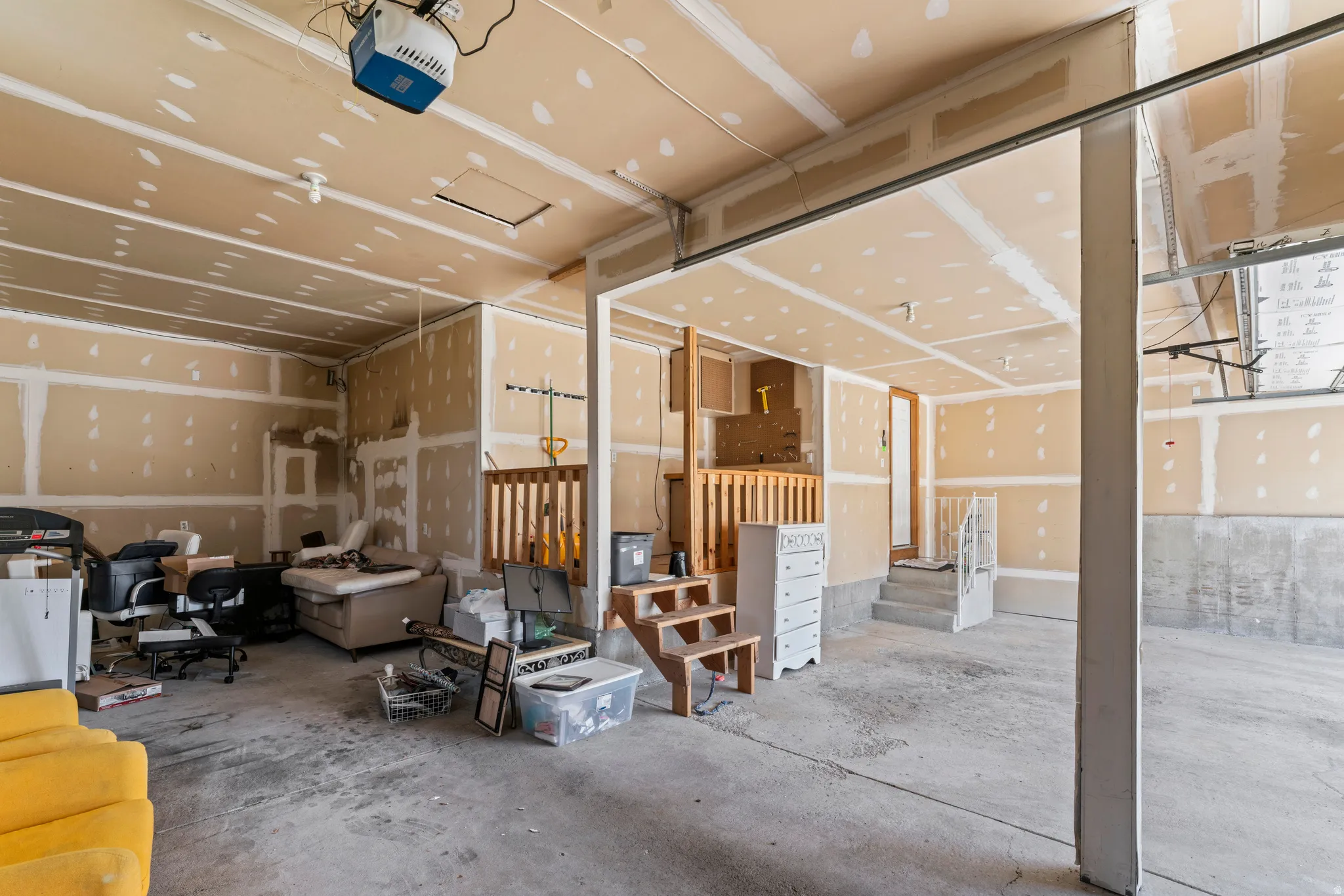 Spacious unfinished garage with concrete flooring, exposed drywall, and an overhead garage door mechanism
