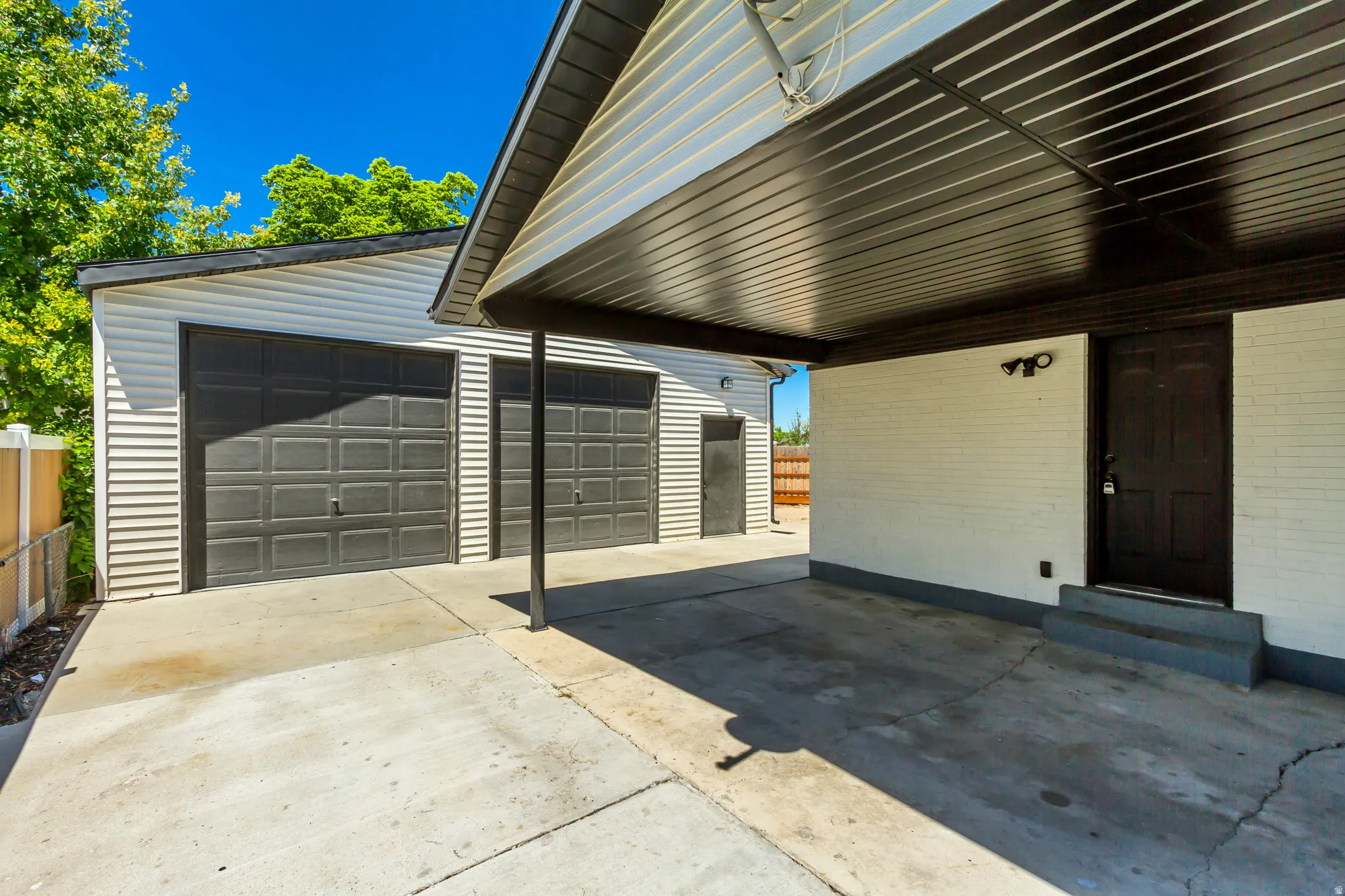 Expansive concrete driveway leading to a four-car garage/shop with dark paneled doors. Garage measures 30'x30'. Extra tall doors.