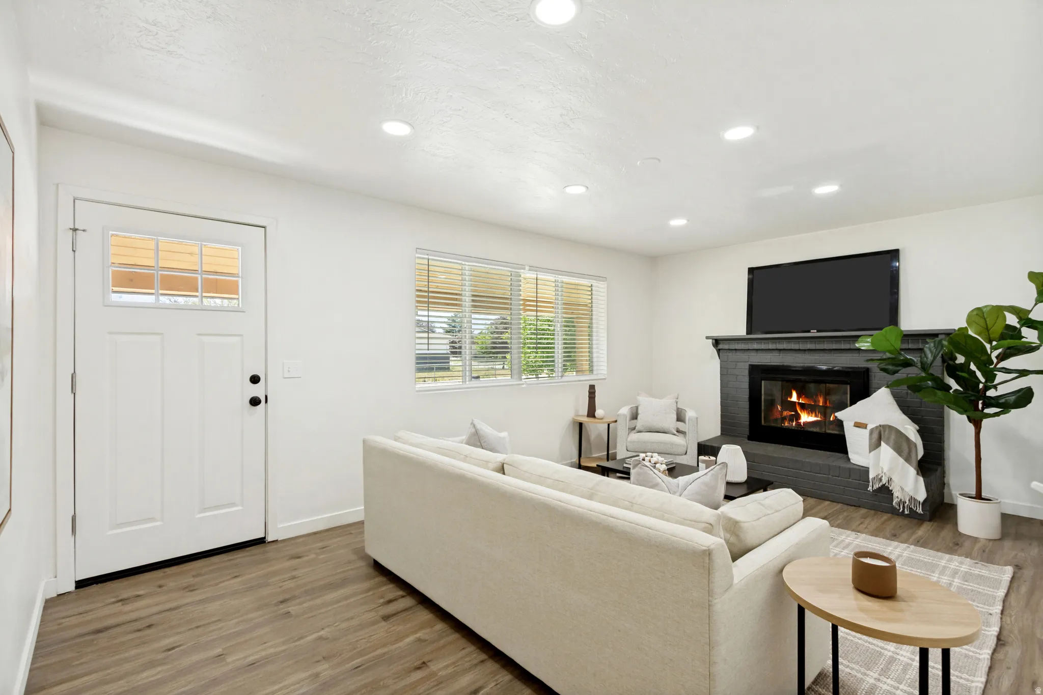 Living area featuring wood-finish flooring, recessed lighting, and a painted brick fireplace with a mantel