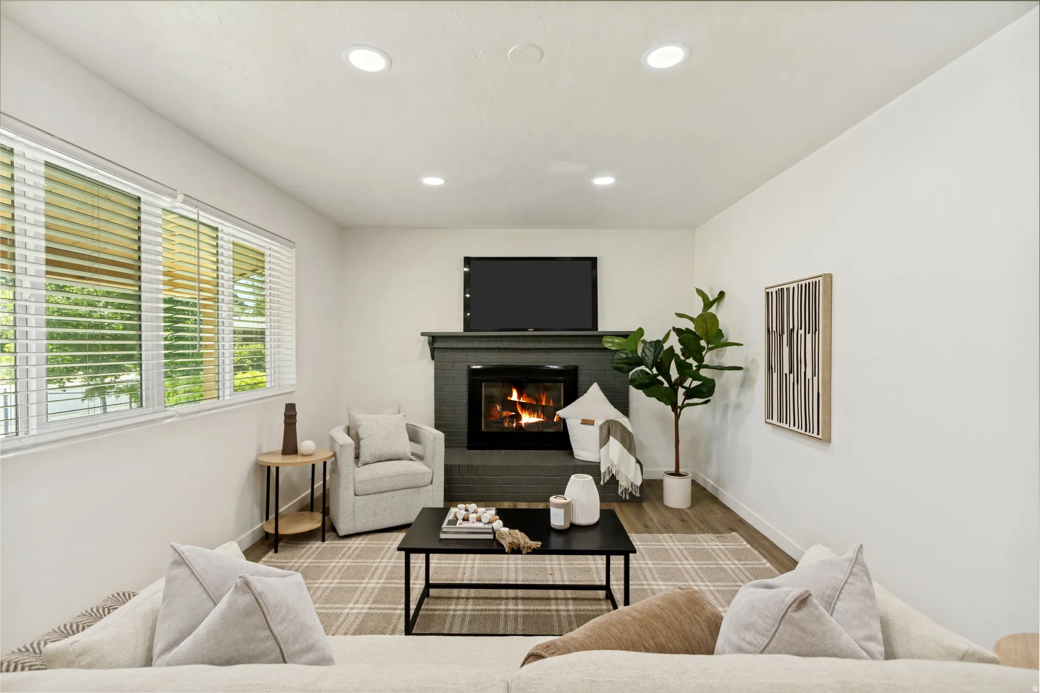 Living area featuring a dark stone fireplace with a mantel, recessed ceiling lighting, and a large window with horizontal blinds