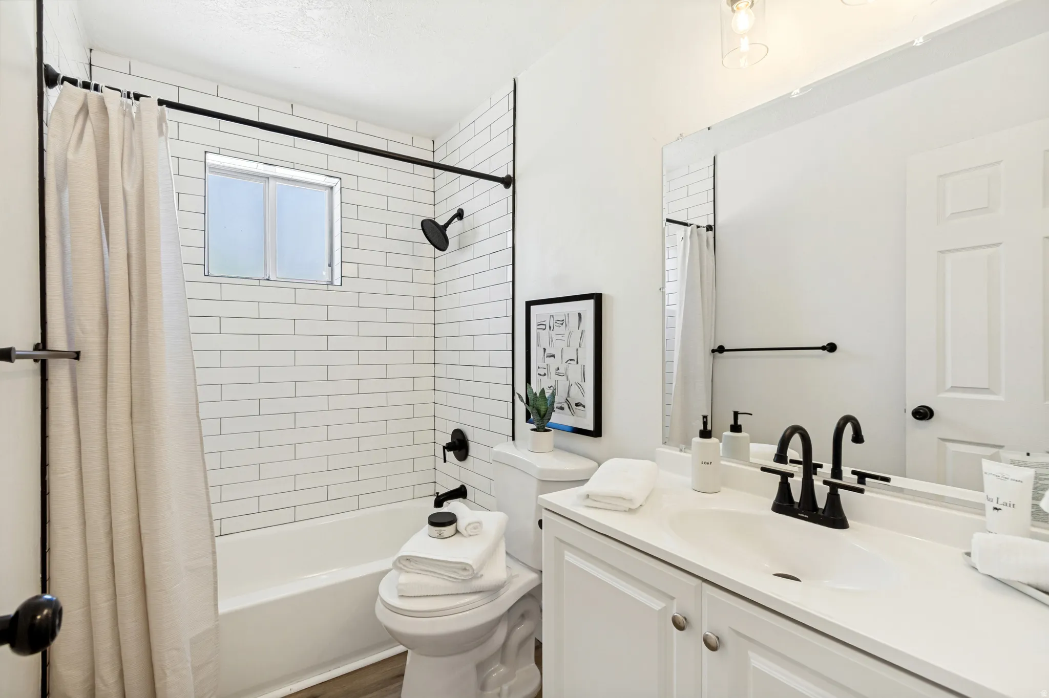 White subway tile shower surround with a built-in window and matte black fixtures