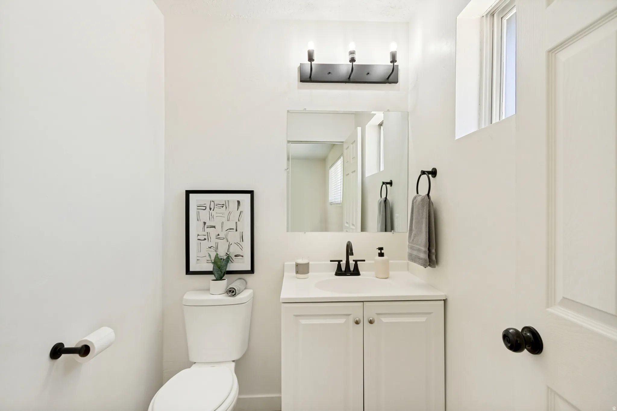 Bathroom featuring a white vanity with a built-in sink, black faucet, and white cabinetry