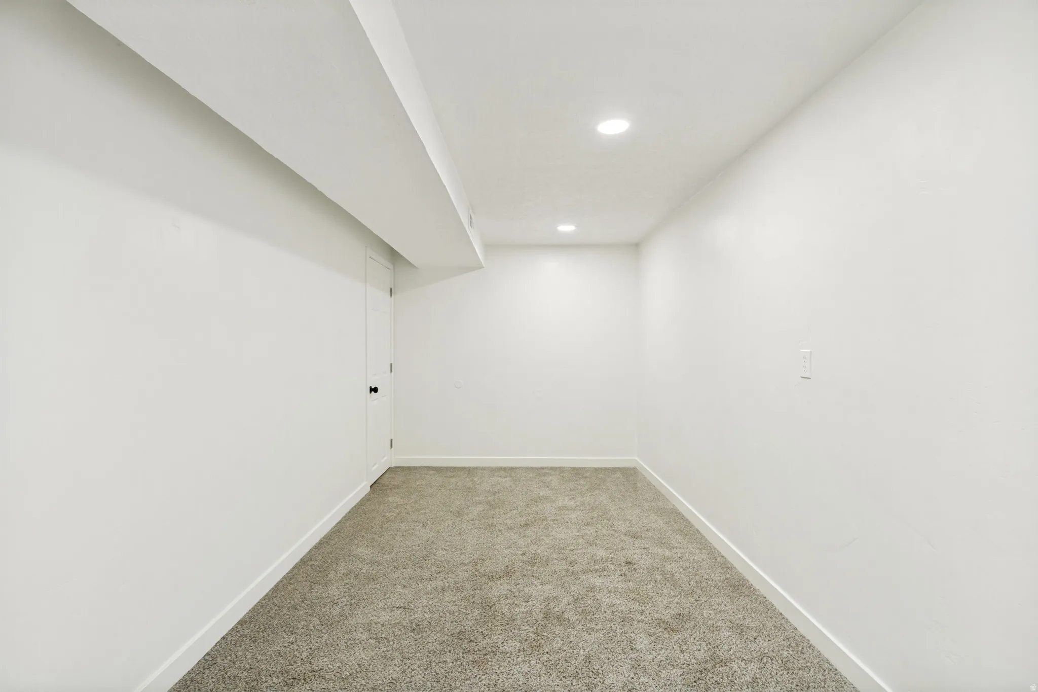 Open-concept room featuring neutral tone carpeting and crisp white walls