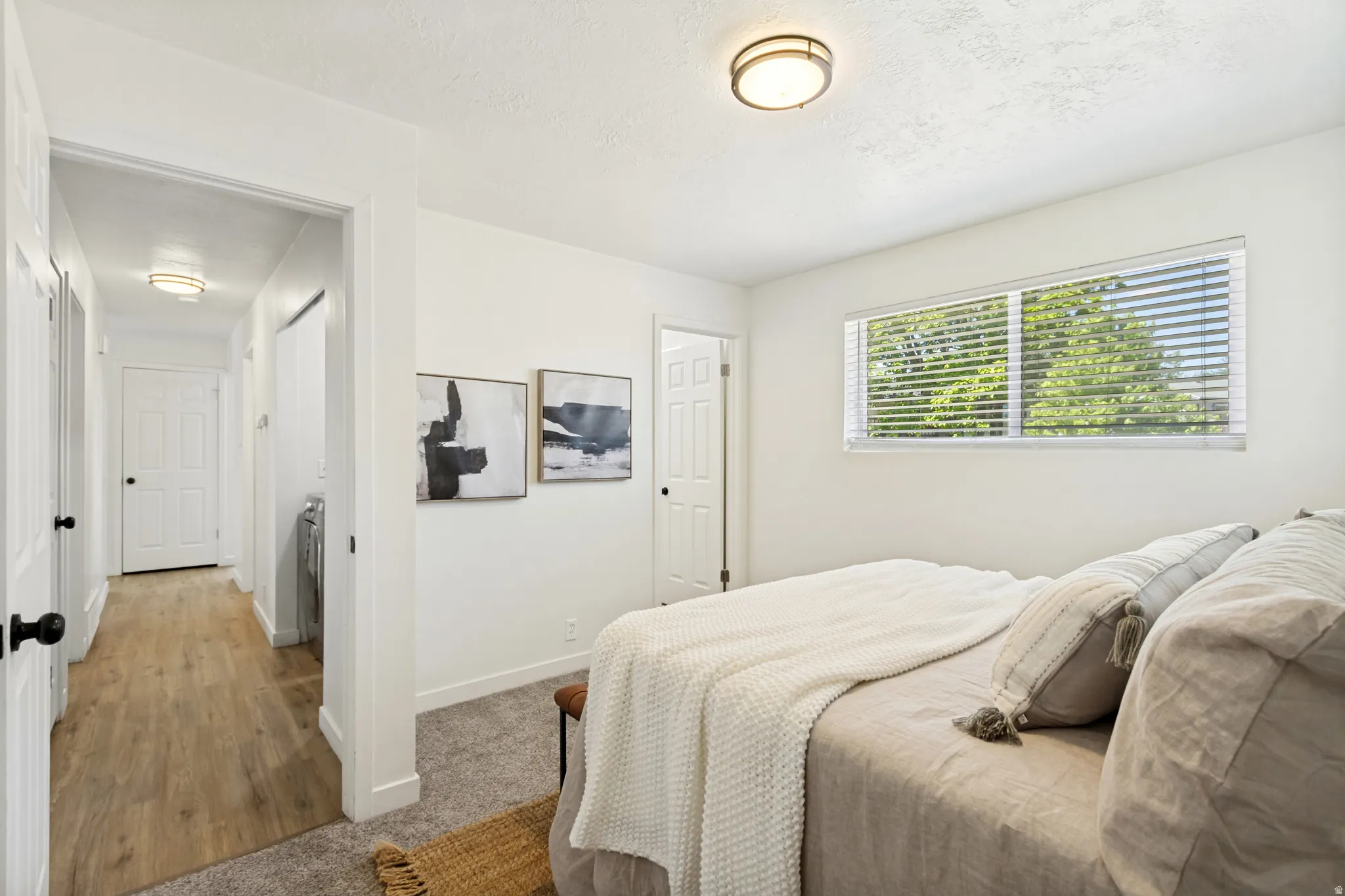 Bedroom featuring a flush-mount ceiling light, a horizontal window with blinds, and light-toned walls