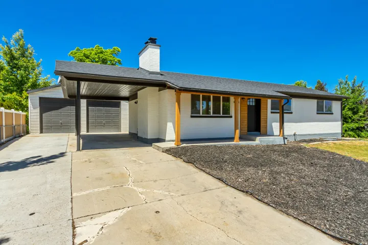 White brick exterior with a dark shingle roof and a covered entryway featuring wood columns