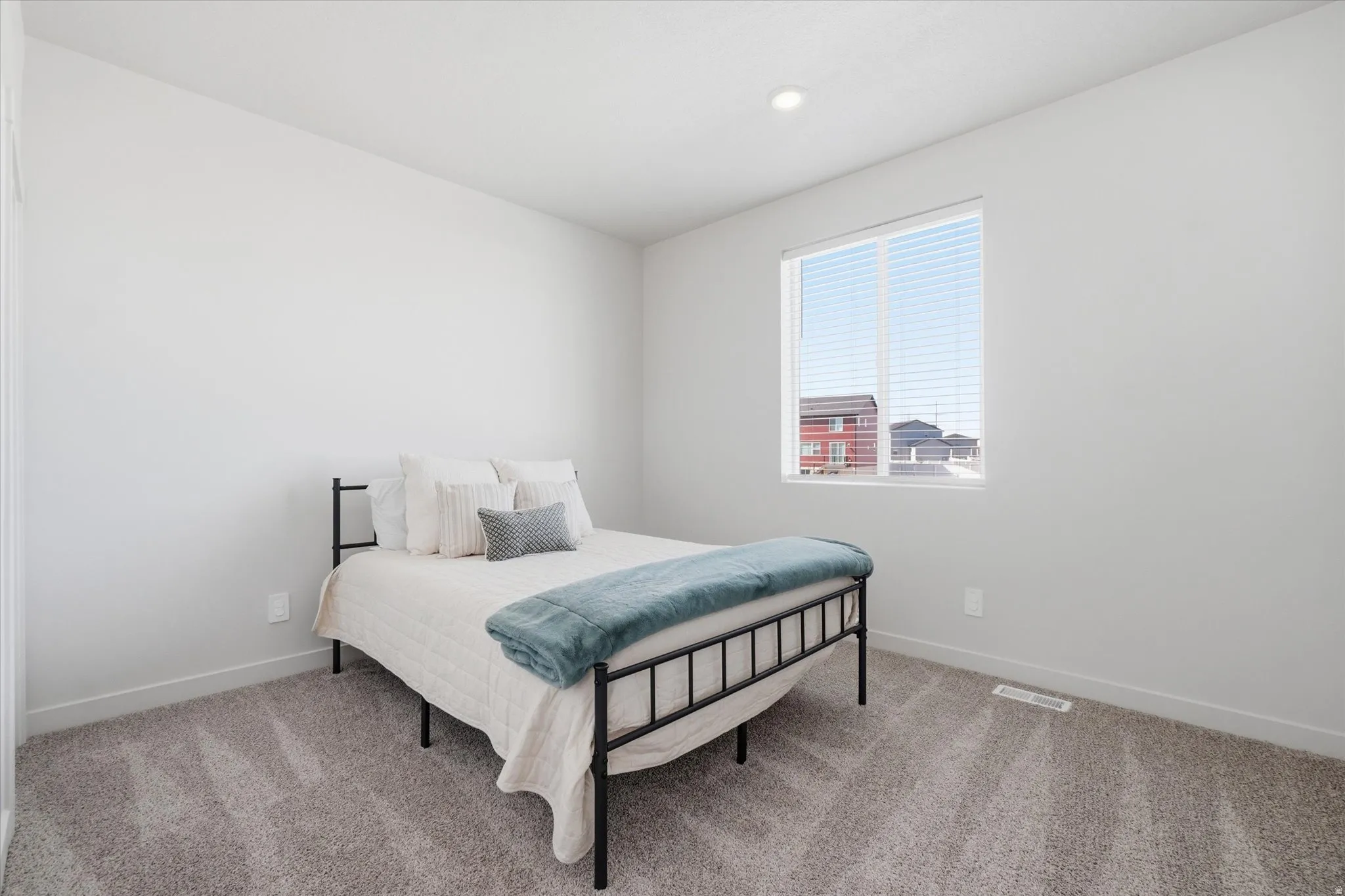 Bedroom featuring plush gray carpeting, a large window with white blinds, recessed ceiling lighting, and a neutral wall color