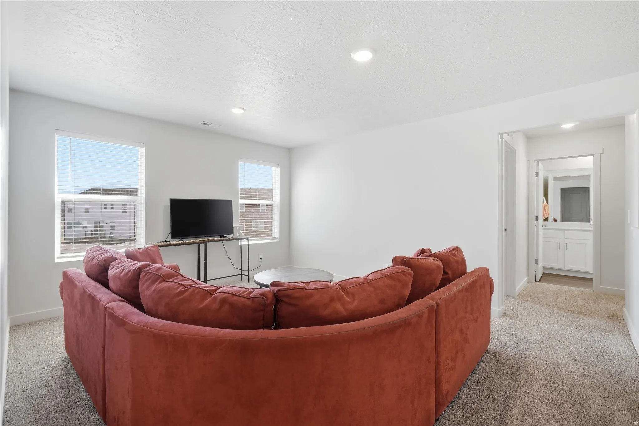 Carpeted living area featuring recessed lighting and two windows with blinds