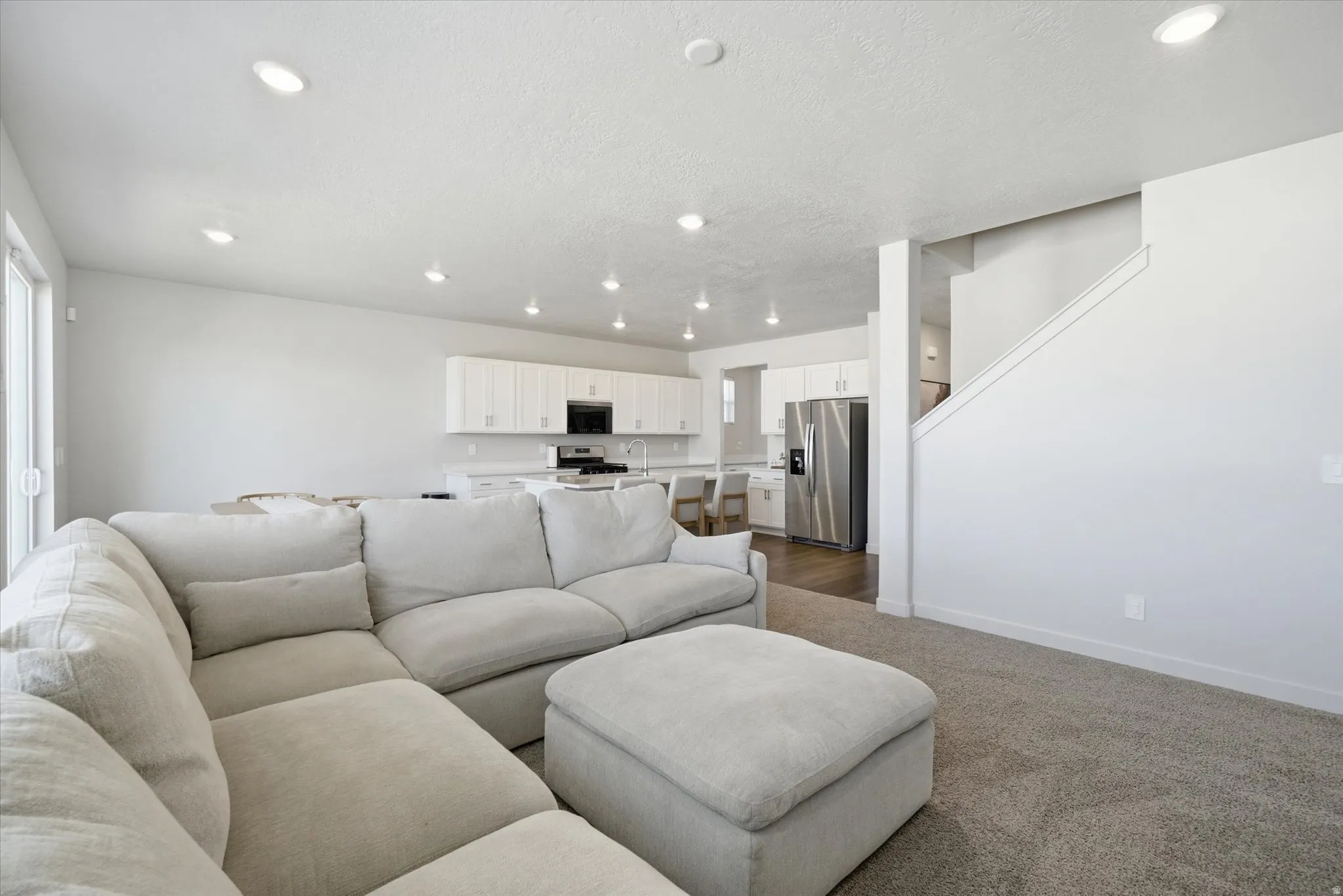 Open-concept living area featuring recessed lighting, a sliding glass door, and neutral-toned carpeting