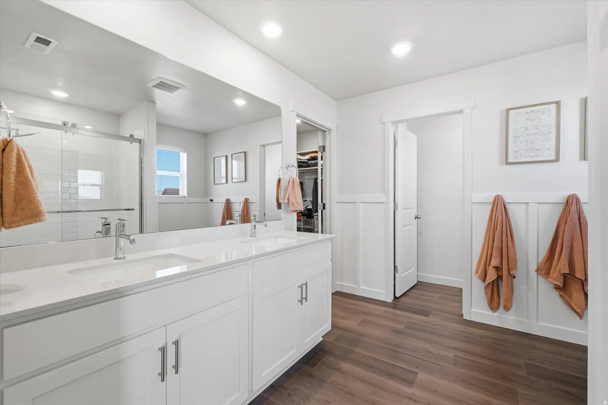 Spacious bathroom featuring a double vanity with stone countertops, modern chrome fixtures, and white cabinetry