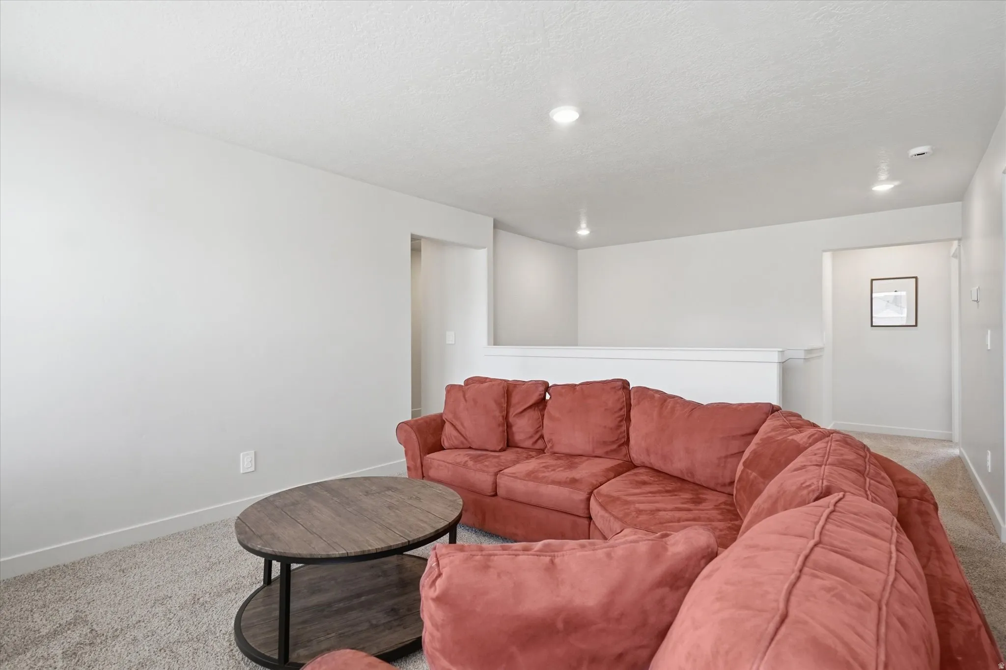 Carpeted living area featuring recessed lighting, a neutral color palette, and a white railing
