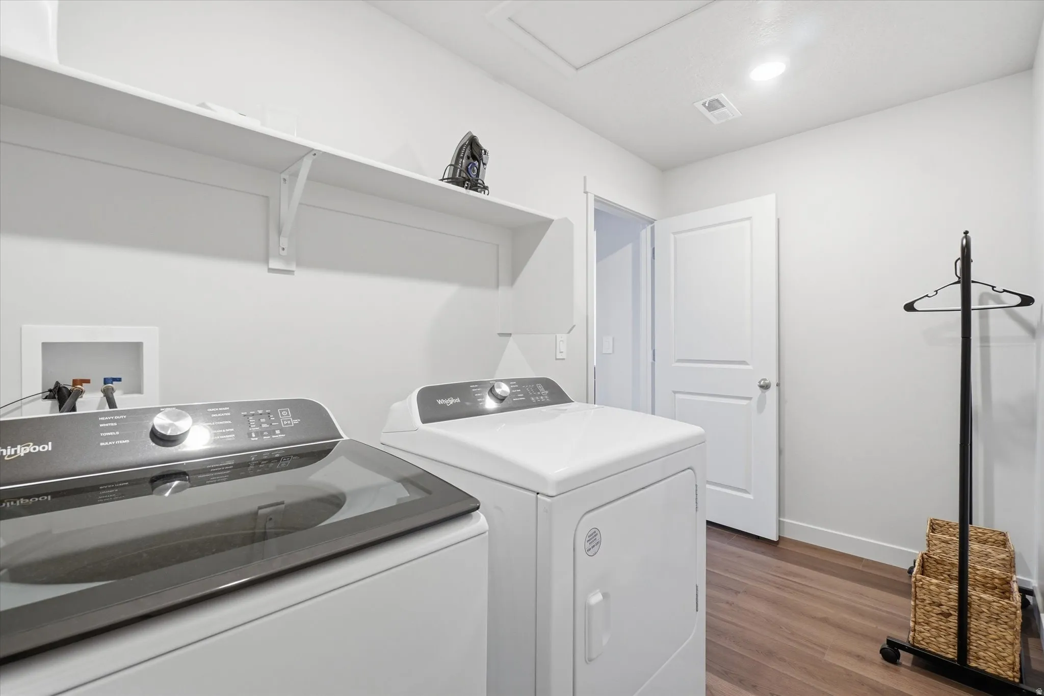 Dedicated laundry room featuring wood-finish flooring and light-toned walls