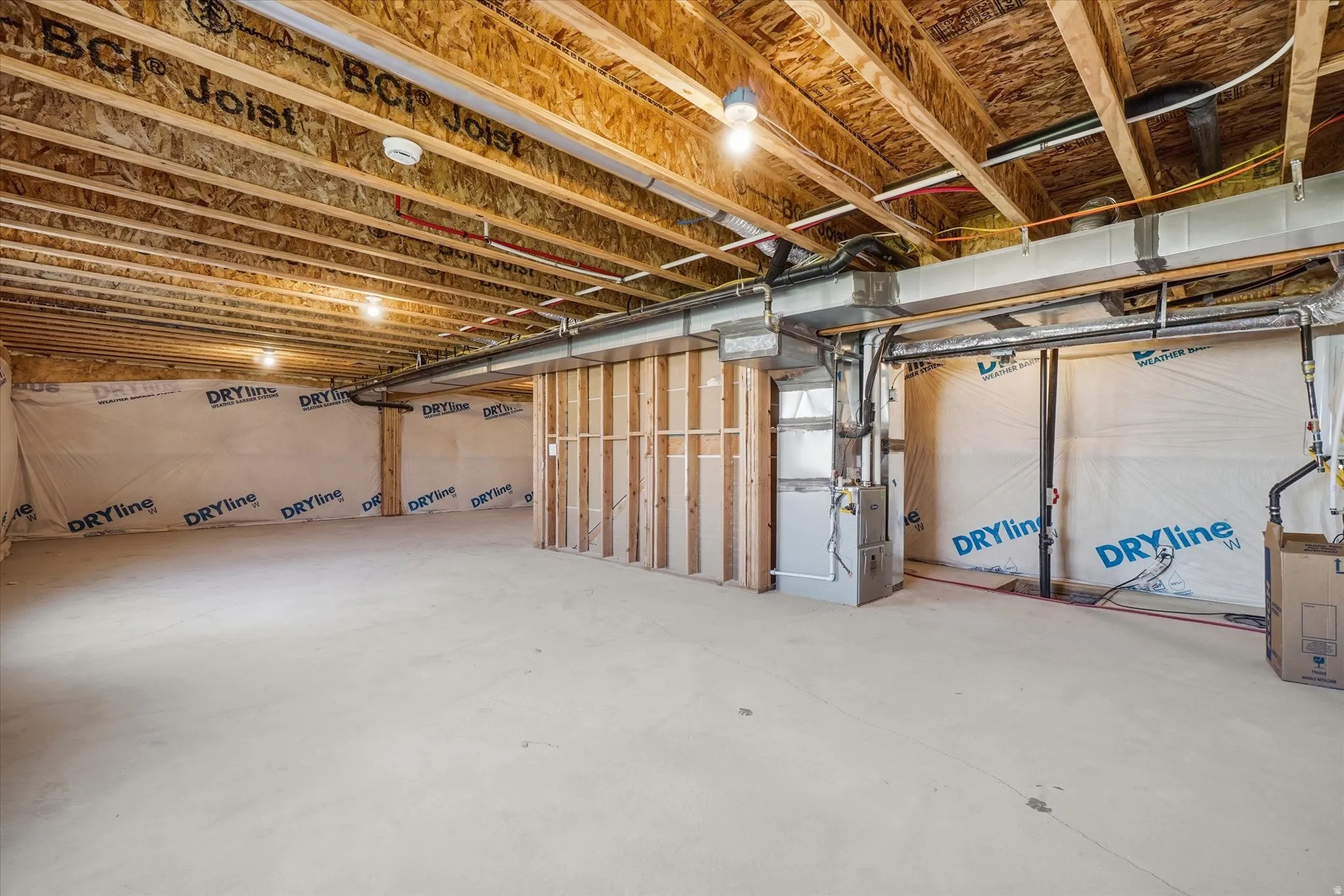 Unfinished basement space featuring exposed wood joists and subfloor, concrete flooring, and perimeter insulation