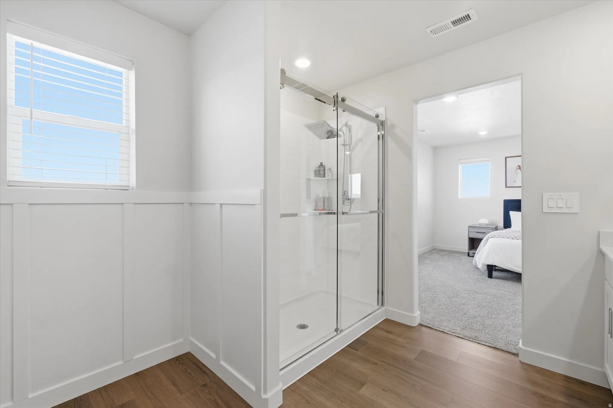 Glass-enclosed shower with sliding door, recessed lighting, and integrated shelving