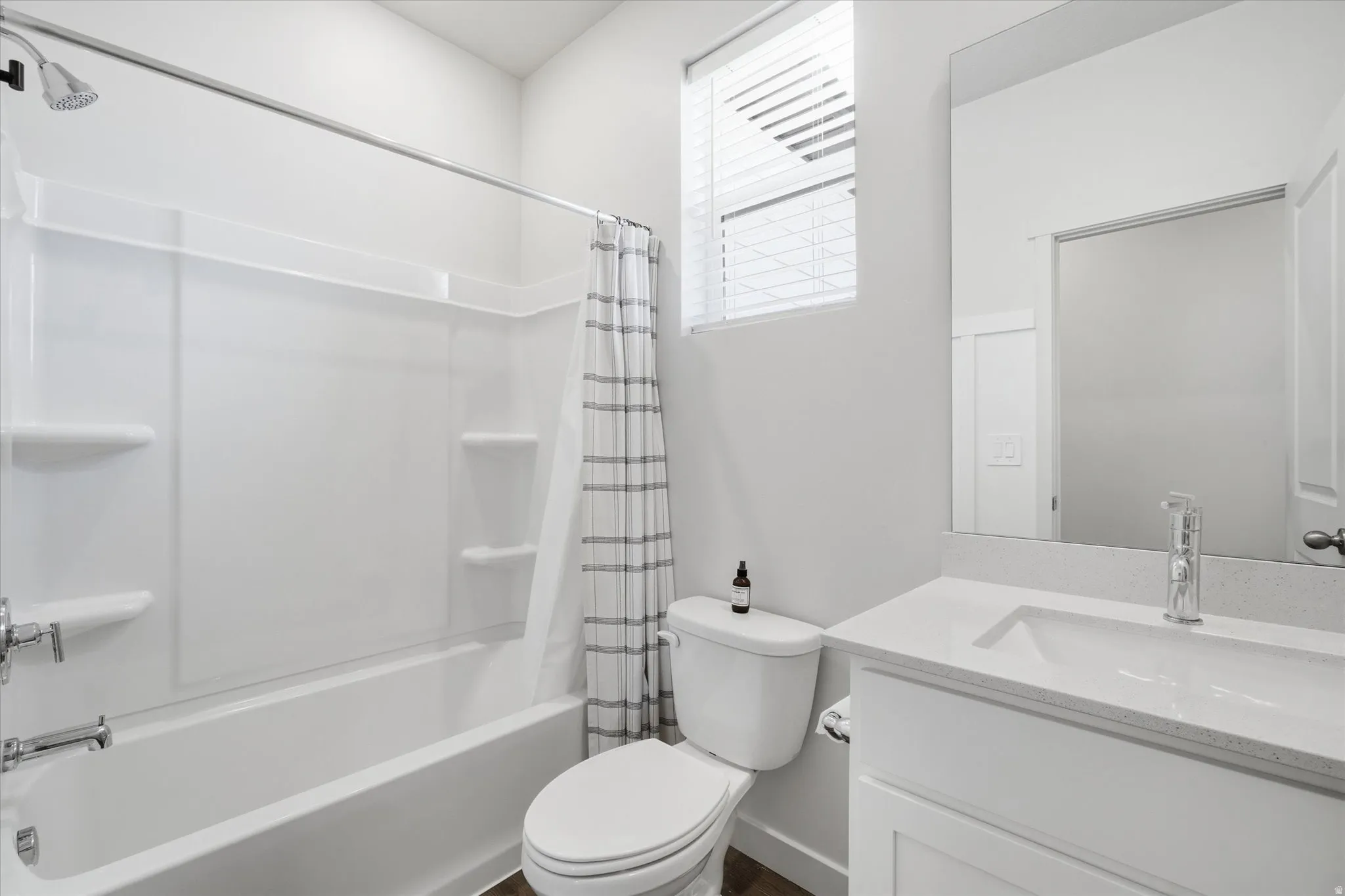 Bathroom featuring a full tub and shower combination with an integrated shelving system, a single vanity with an undermount sink and light-colored countertop, and modern chrome fixtures