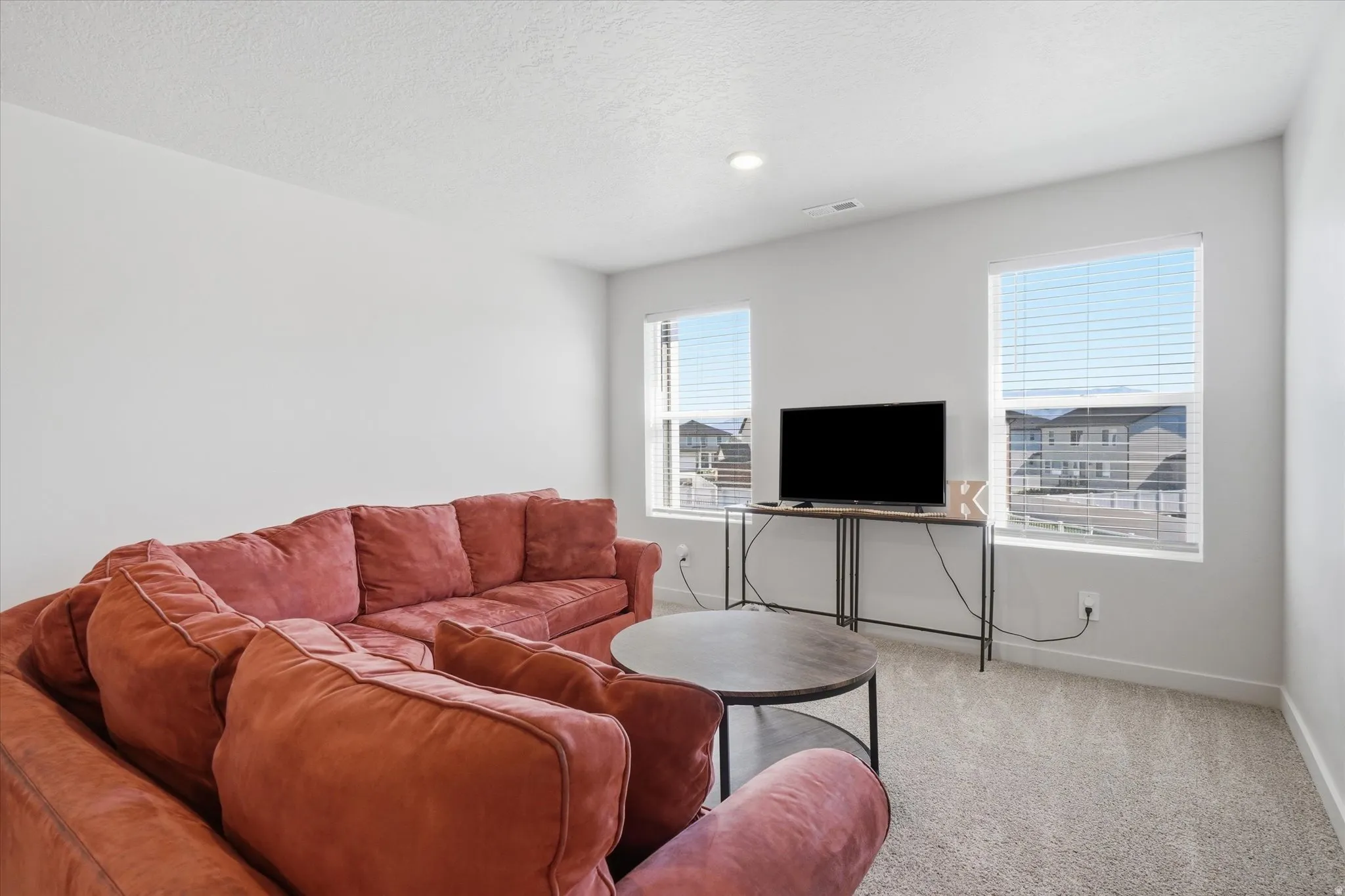 Carpeted room featuring two windows with horizontal blinds, providing natural light