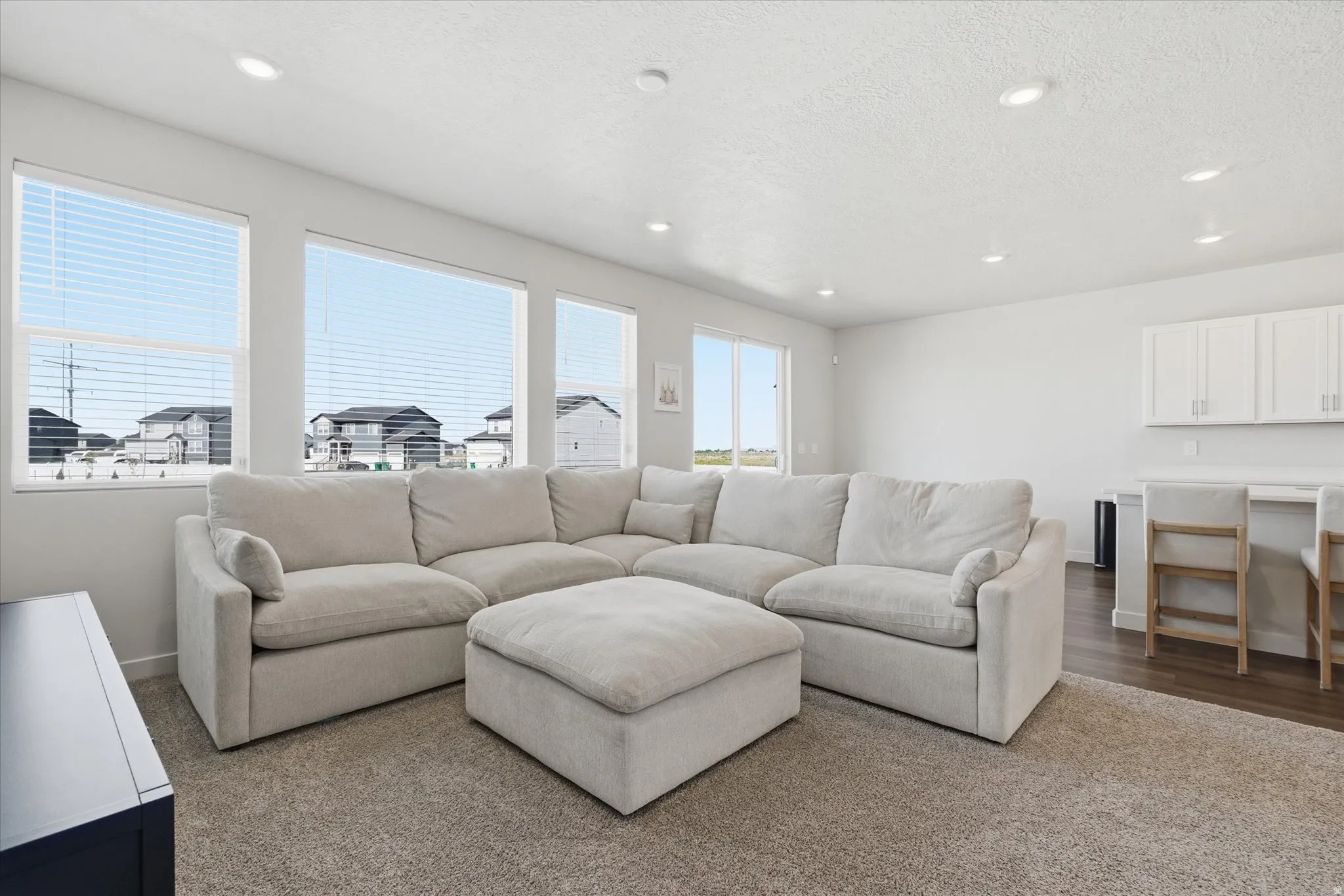 Bright living area featuring multiple windows, recessed lighting, and a built-in countertop with upper cabinetry
