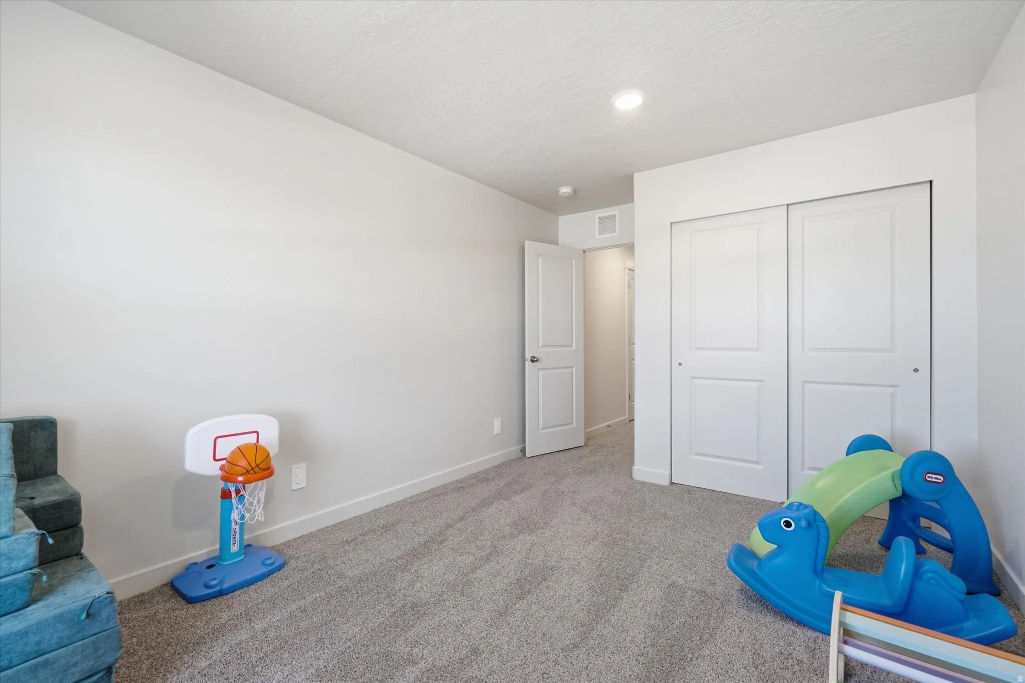 Carpeted interior room featuring light gray walls, a white paneled door, and a white bi-fold closet with panel details