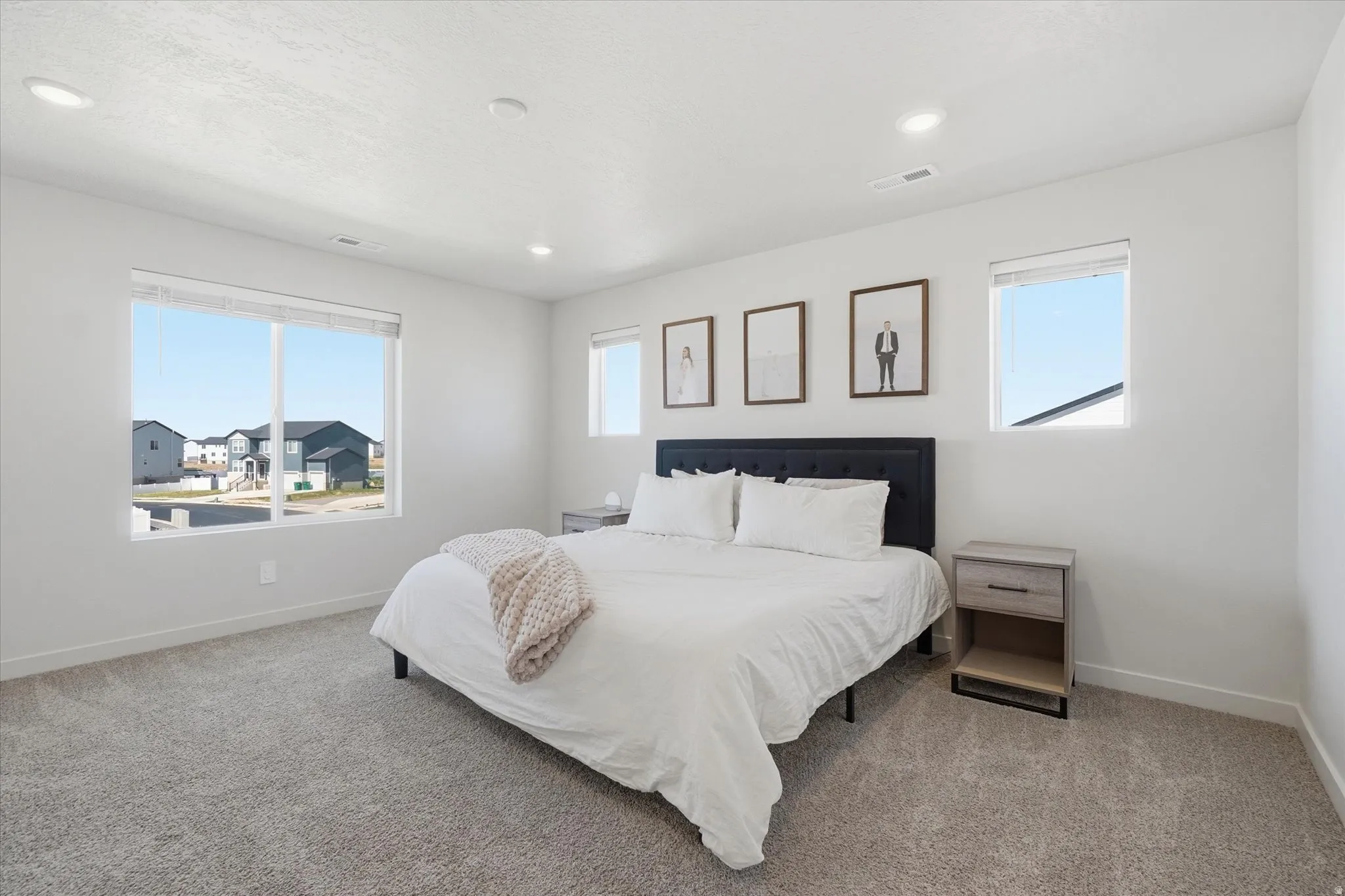 Spacious room featuring neutral carpeting, a large picture window, and two smaller windows providing ambient light
