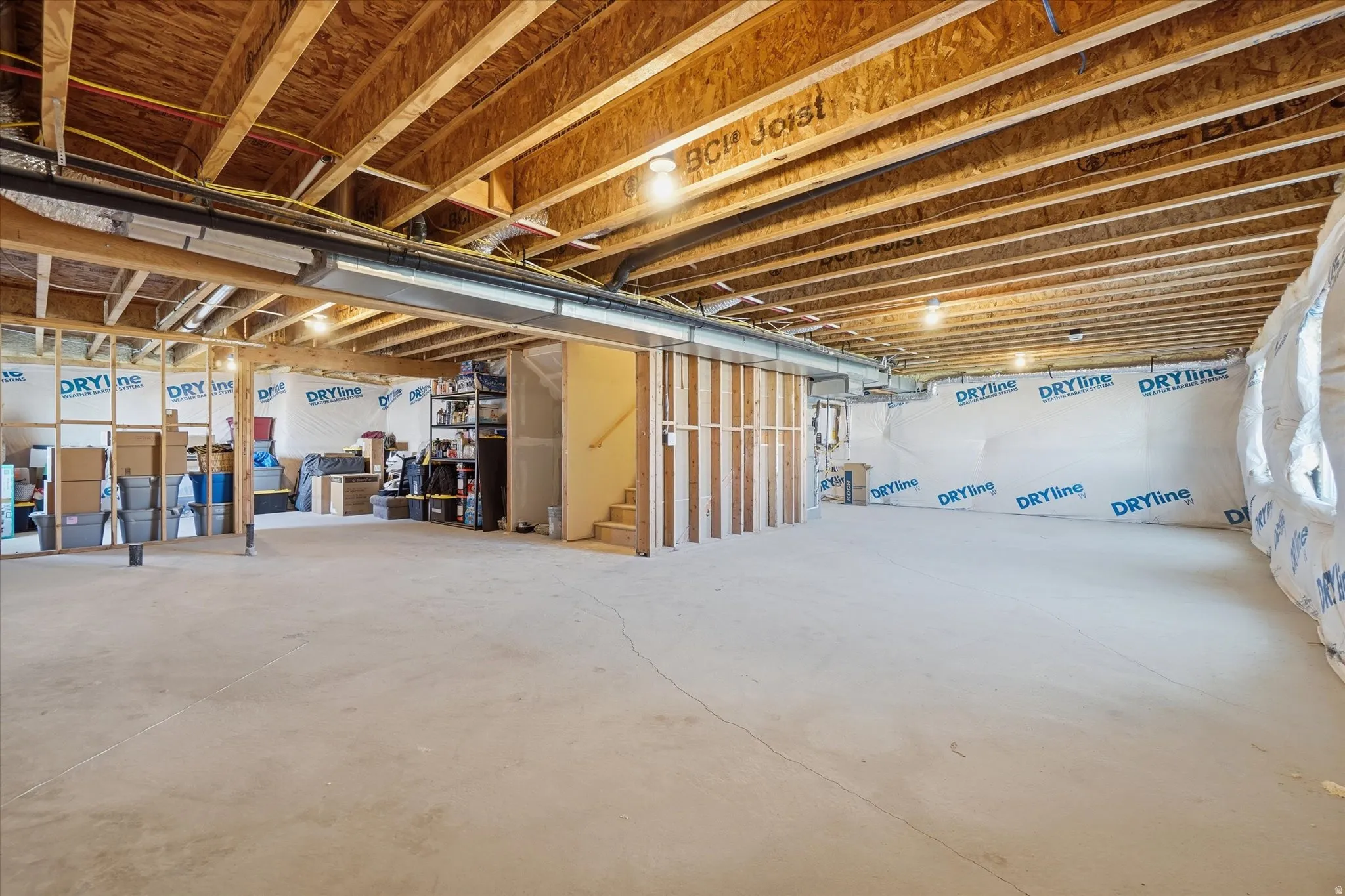 Expansive unfinished lower level featuring exposed wood joists and concrete flooring