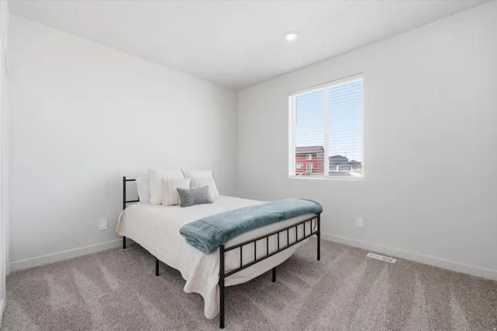 Bedroom featuring plush gray carpeting, a large window with white blinds, recessed ceiling lighting, and a neutral wall color