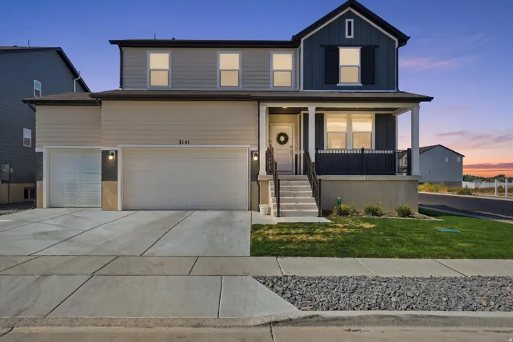 Contemporary two-story residence featuring a covered front porch, dual garage doors, and multi-toned siding