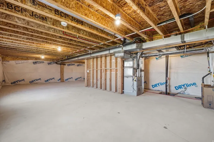 Unfinished basement space featuring exposed wood joists and subfloor, concrete flooring, and perimeter insulation