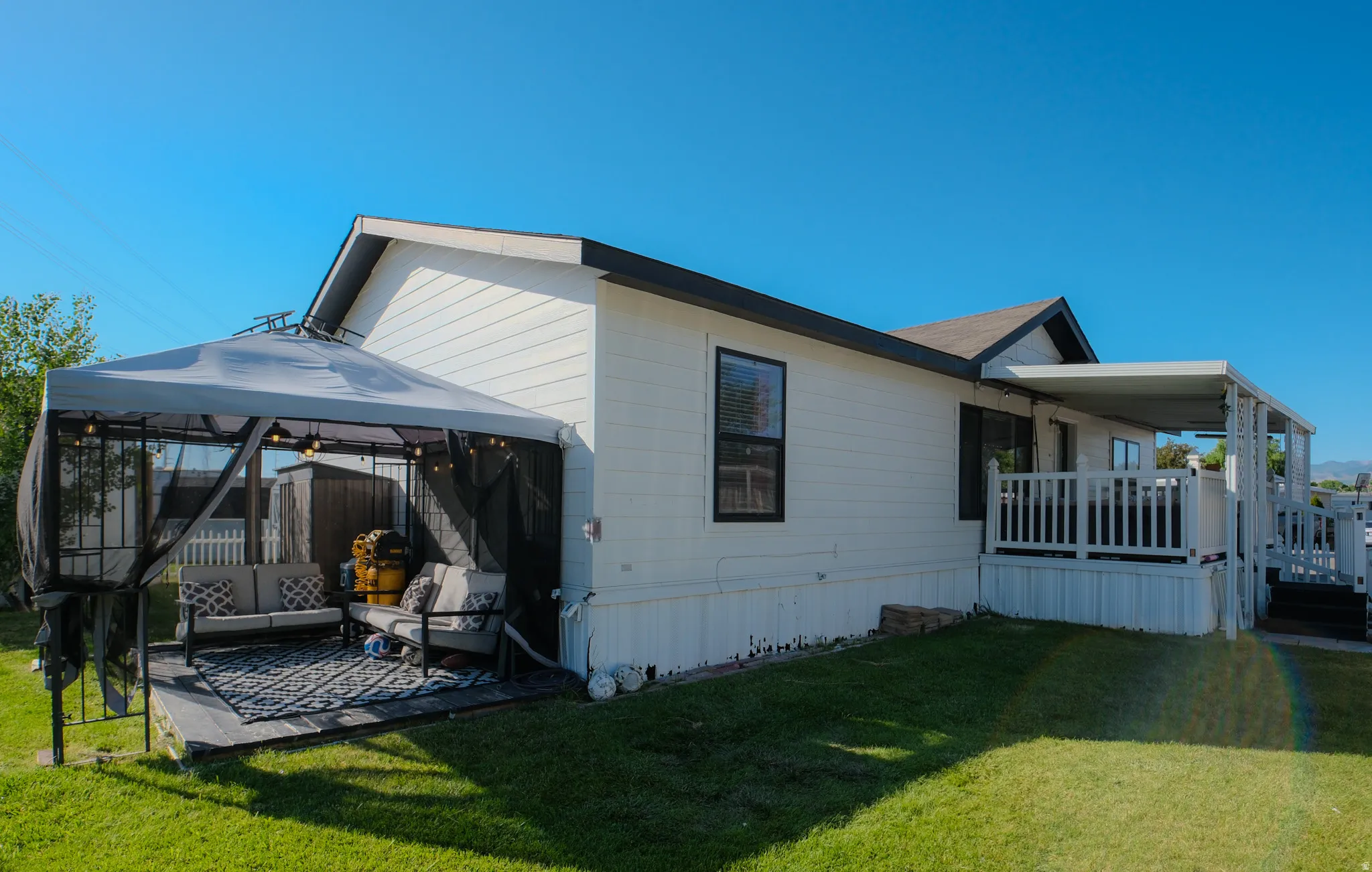 White horizontal siding exterior with dark trim and a covered deck featuring a white railing