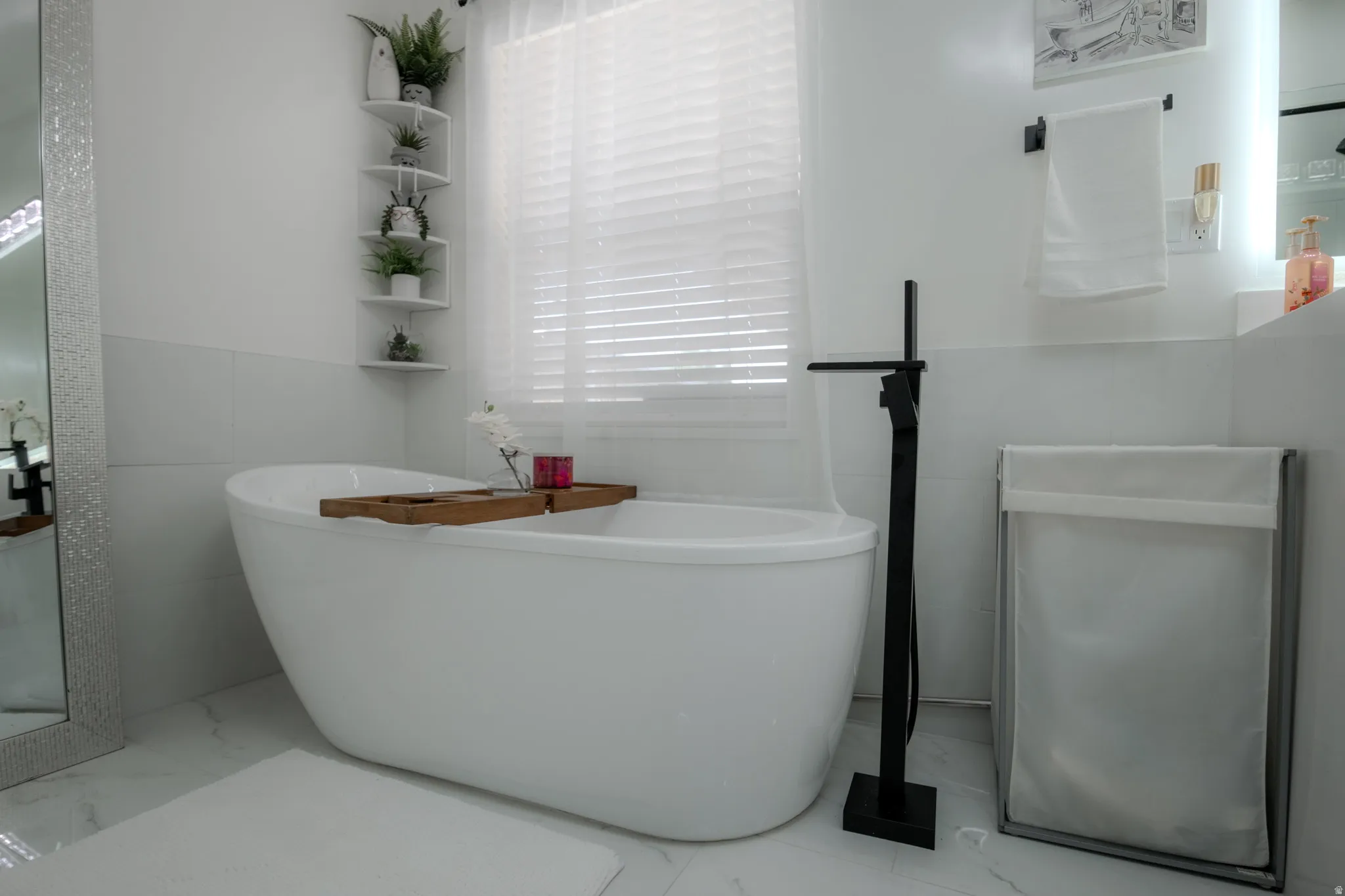 Freestanding soaking tub featuring a matte black floor-mounted faucet