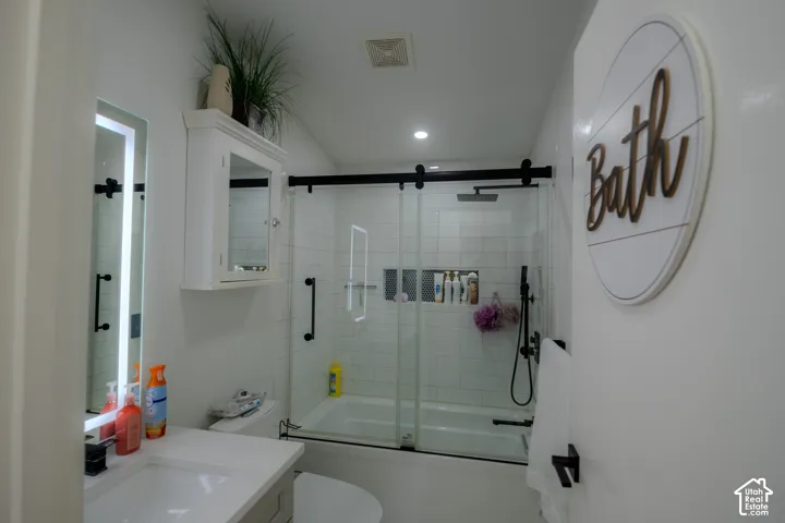 Modern bathroom featuring a tiled tub/shower combination with a sliding glass door and matte black hardware