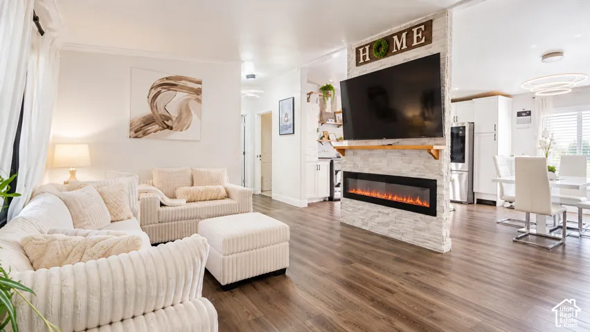 Central stone-clad partition wall featuring a built-in linear electric fireplace and wood mantel, finished with wide-plank wood-finish flooring and modern circular ring lighting fixtures