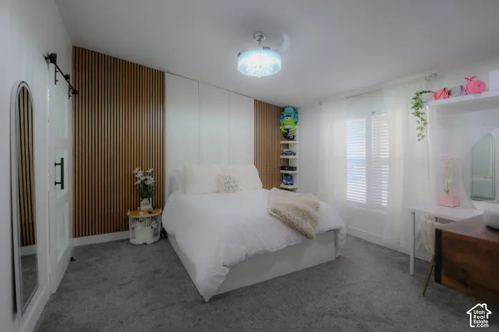 Bedroom featuring a wood-panel accent wall and soft gray carpeting