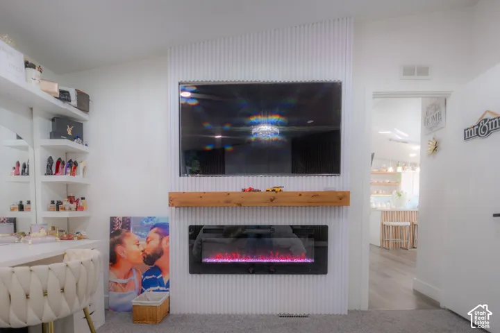 Feature wall with a mounted television above a wood mantel and an electric fireplace
