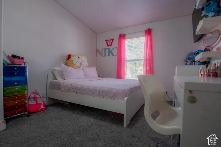 Carpeted room with a double-hung window, white walls, and a sloped ceiling
