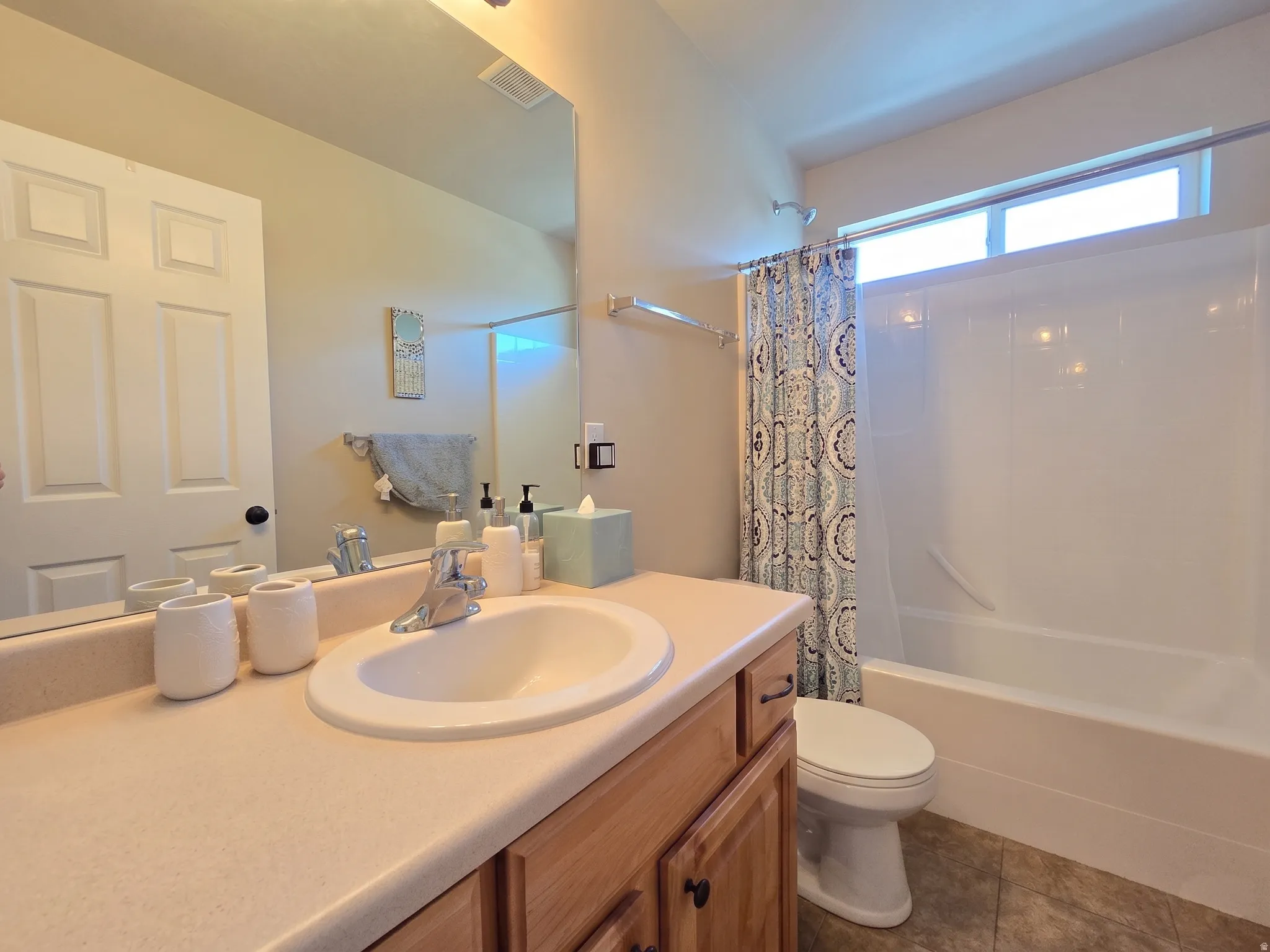 Bathroom featuring a light-toned vanity with an integrated sink, wood-finish cabinetry, and a large wall-mounted mirror