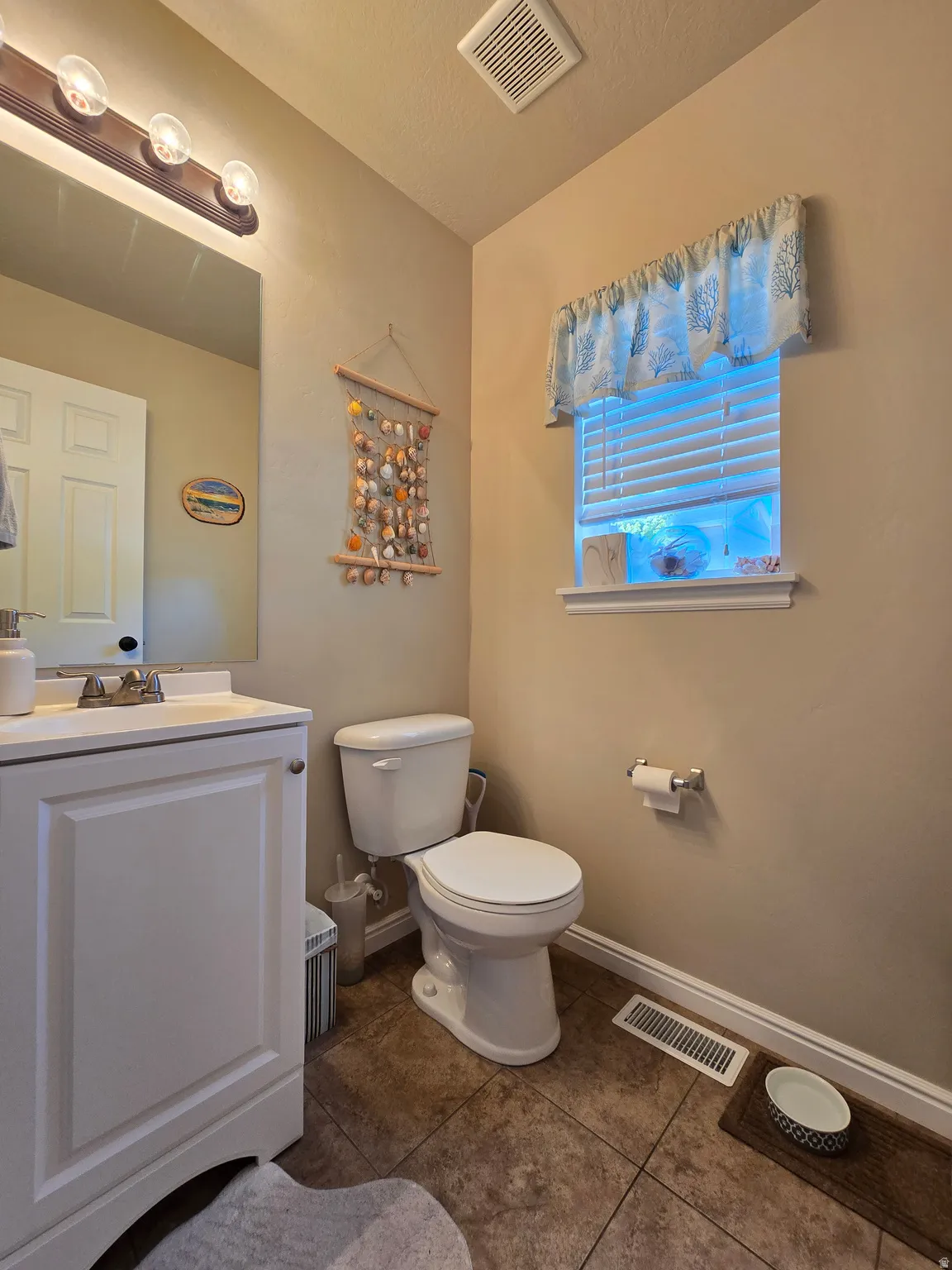 Bathroom featuring a white vanity with a single basin, a chrome faucet, and a large wall-mounted mirror