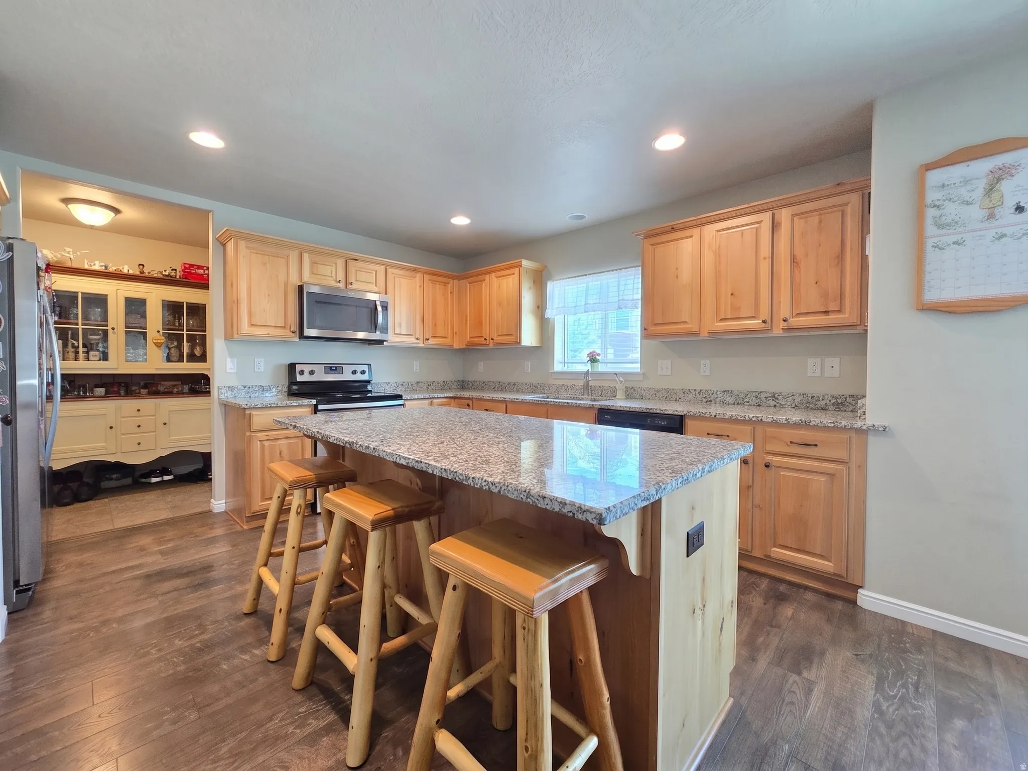 Kitchen featuring natural wood cabinetry, granite countertops, and wood-finish flooring