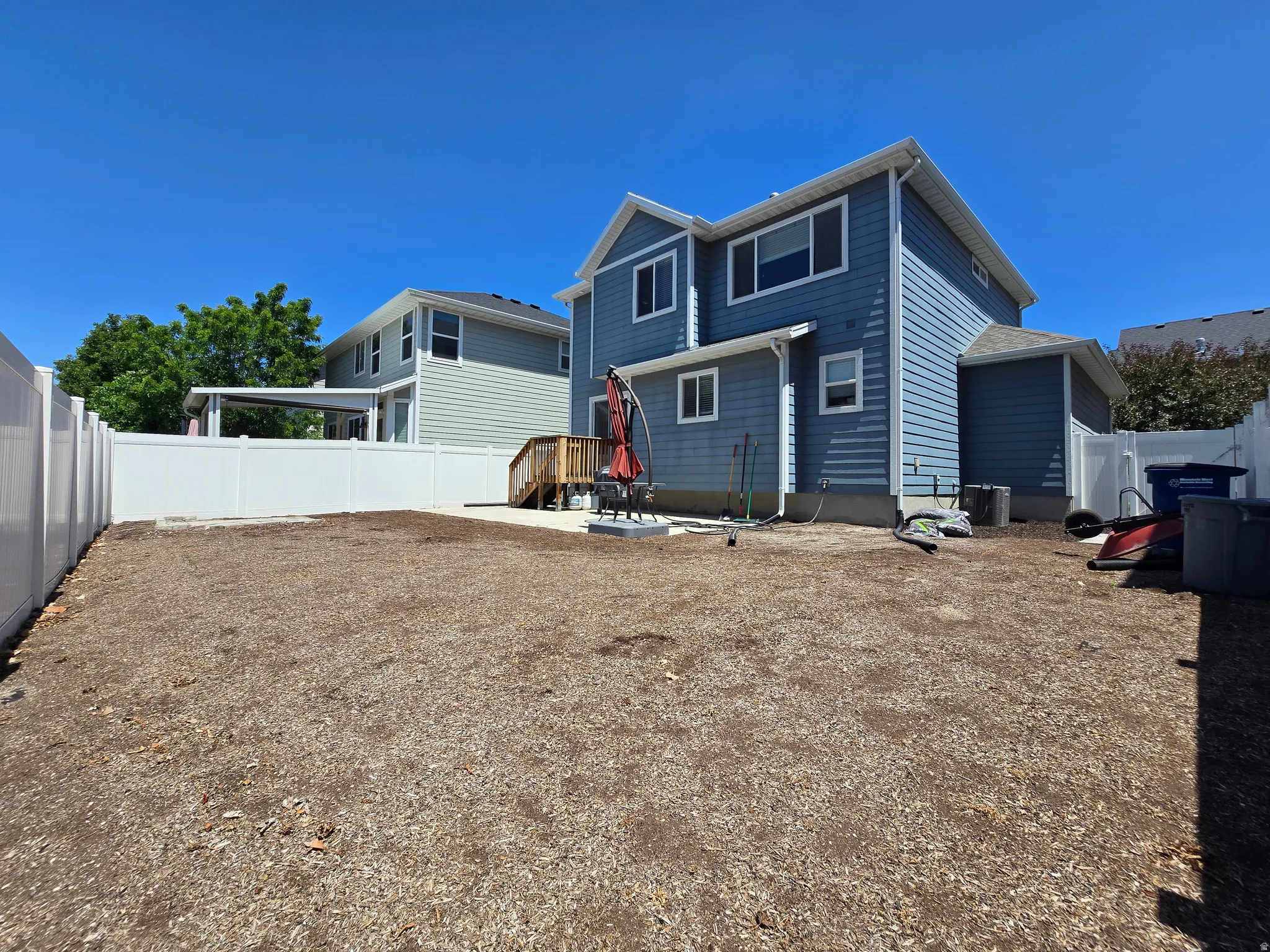 Spacious backyard featuring a large gravel-covered area, a white vinyl privacy fence, and a concrete patio