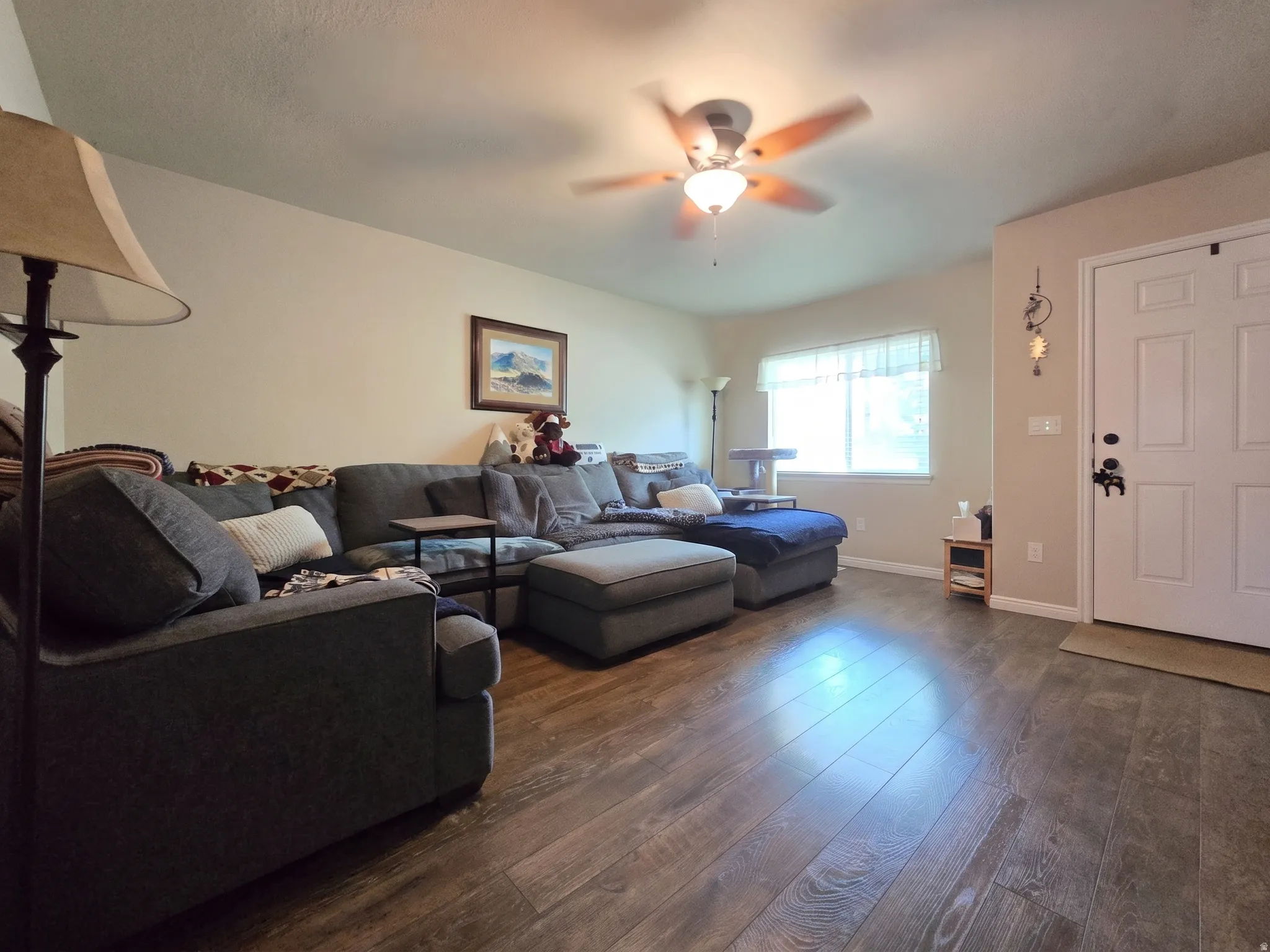 Spacious living area featuring wood-finish flooring and a ceiling fan with integrated lighting