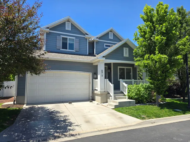 Two-story exterior featuring blue siding, white trim, a covered entry porch with railing, an integrated garage, and a concrete driveway