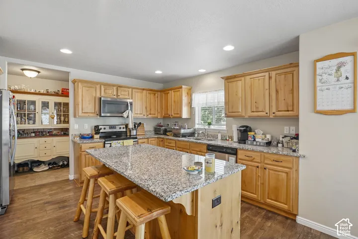 Kitchen featuring wood-finish flooring, recessed lighting, and a center island with a stone-look countertop