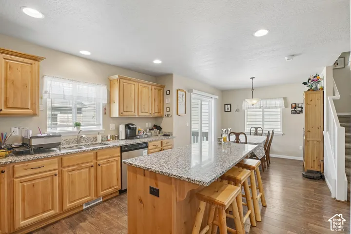 Kitchen featuring wood cabinetry, granite countertops, stainless steel appliances, and a central island with bar seating