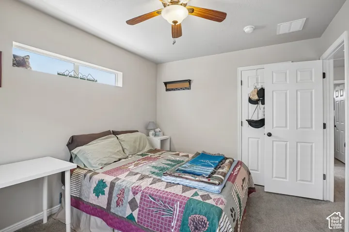 Carpeted room featuring a ceiling fan with light fixture, high transom window, white panel doors, and neutral wall paint