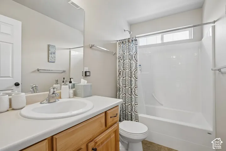 Bathroom featuring a single vanity with wood cabinetry, an integrated sink, a large wall mirror, and a shower-over-tub combination with a transom window