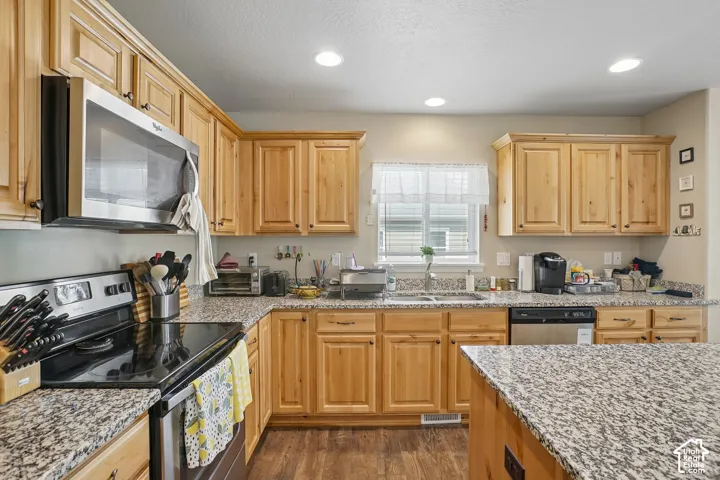 Kitchen featuring wood-finish cabinetry, speckled countertops, and stainless steel appliances